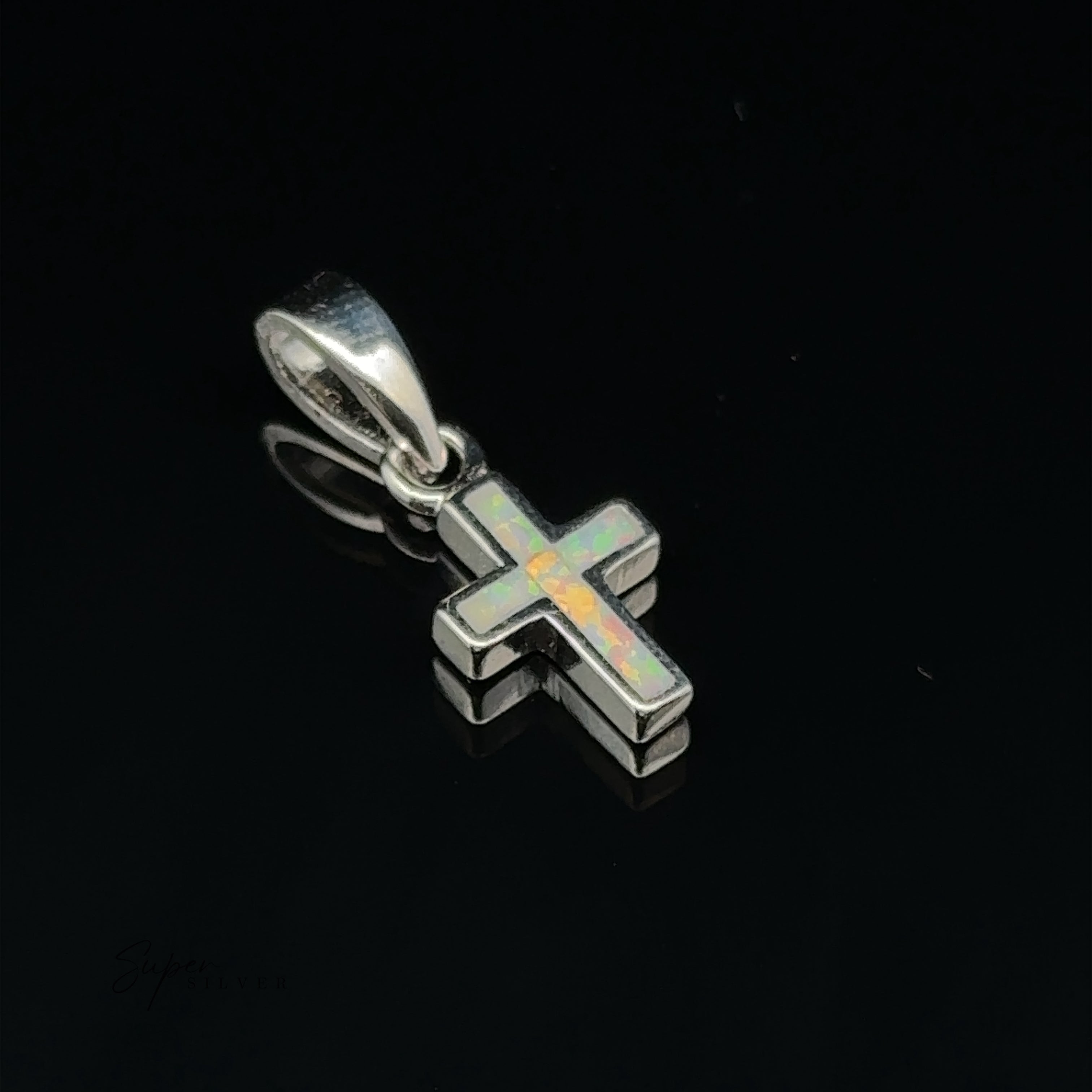 Close-up of a Lab-Created Opal Cross Pendant, featuring a minimalist design in sterling silver with an iridescent opal inlay, set against a black background.