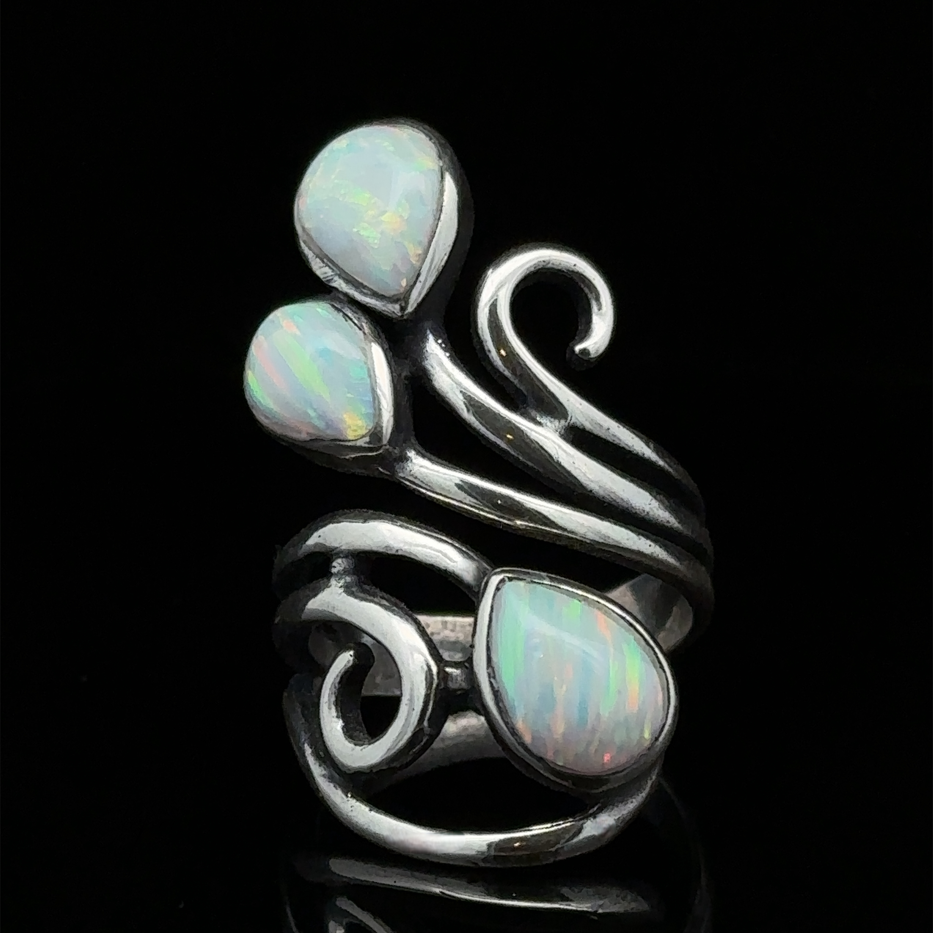 A sterling silver ring with a floral design featuring three white opal stones set against a black background, the Stunning Wrap-Around Opal Ring is truly captivating.