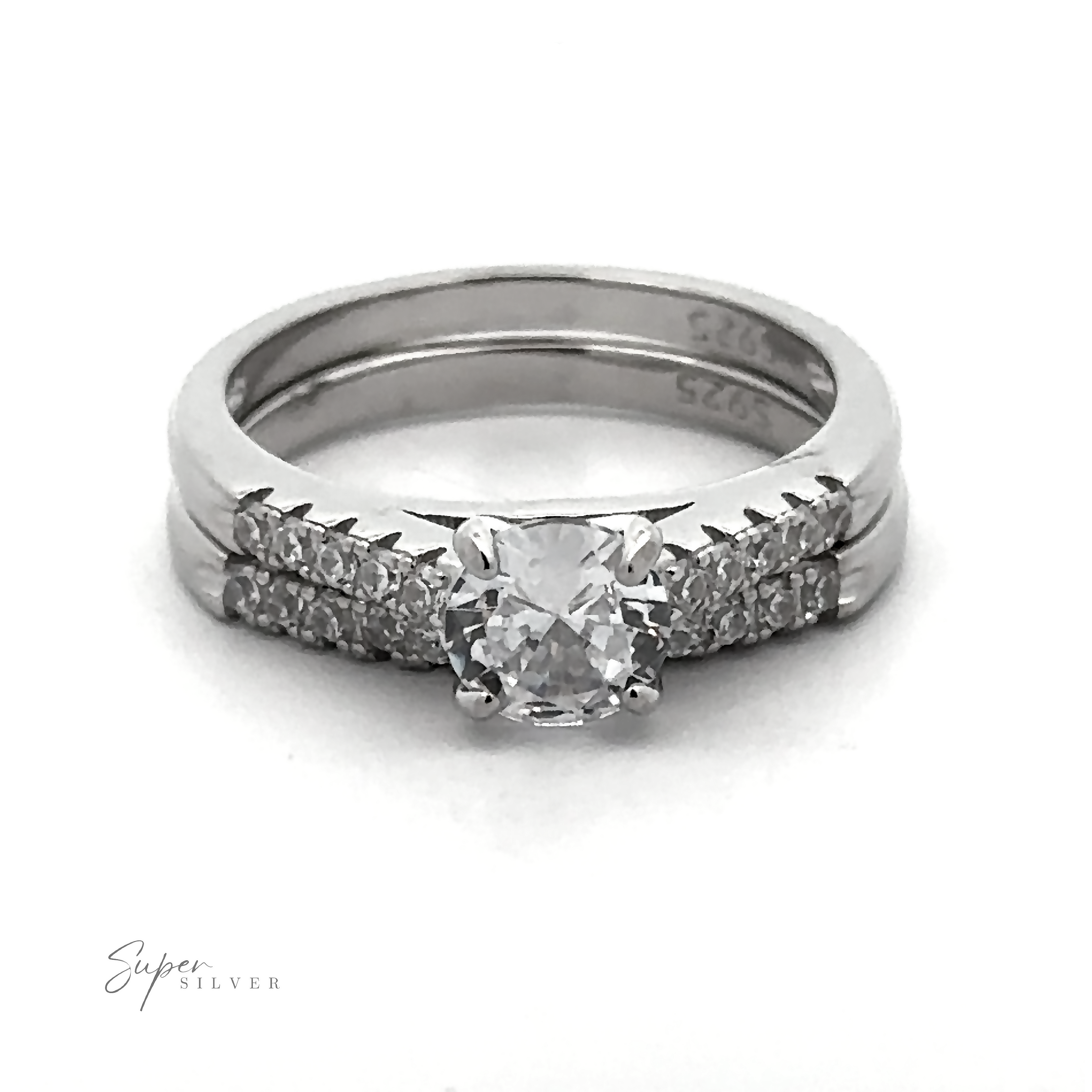 Introducing the Round Solitaire Wedding Band Set: a stunning sterling silver engagement ring with a central diamond, accentuated by small diamonds on the band. The set is complemented by a matching wedding band featuring cubic zirconia. Both rings are inscribed with "925," highlighting their exquisite quality rhodium finish.
