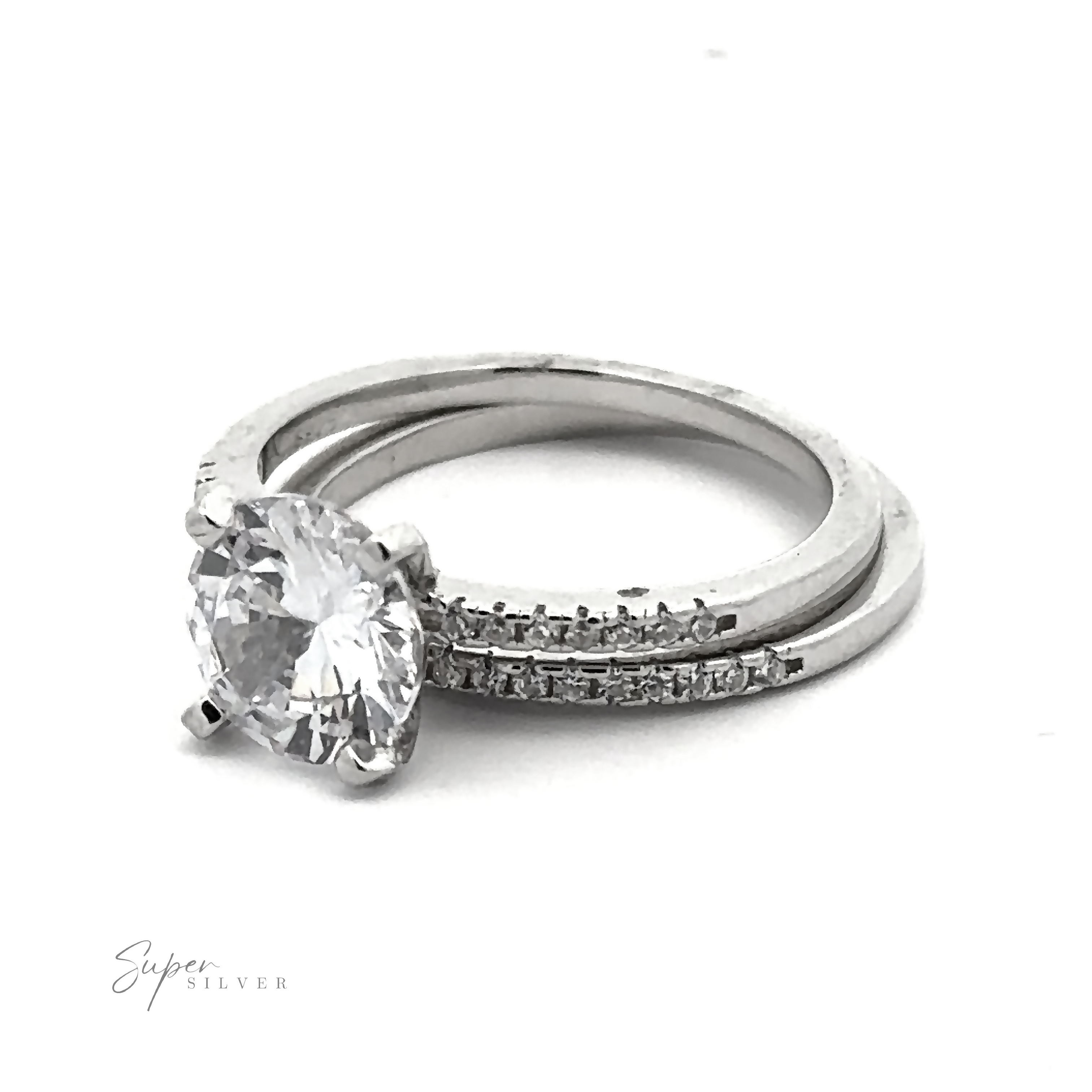 A Round Cubic Zirconia Wedding Set Ring features a large round center diamond, paired with a matching wedding band adorned with pave accents. "Super Silver" is faintly visible in the bottom left corner.
