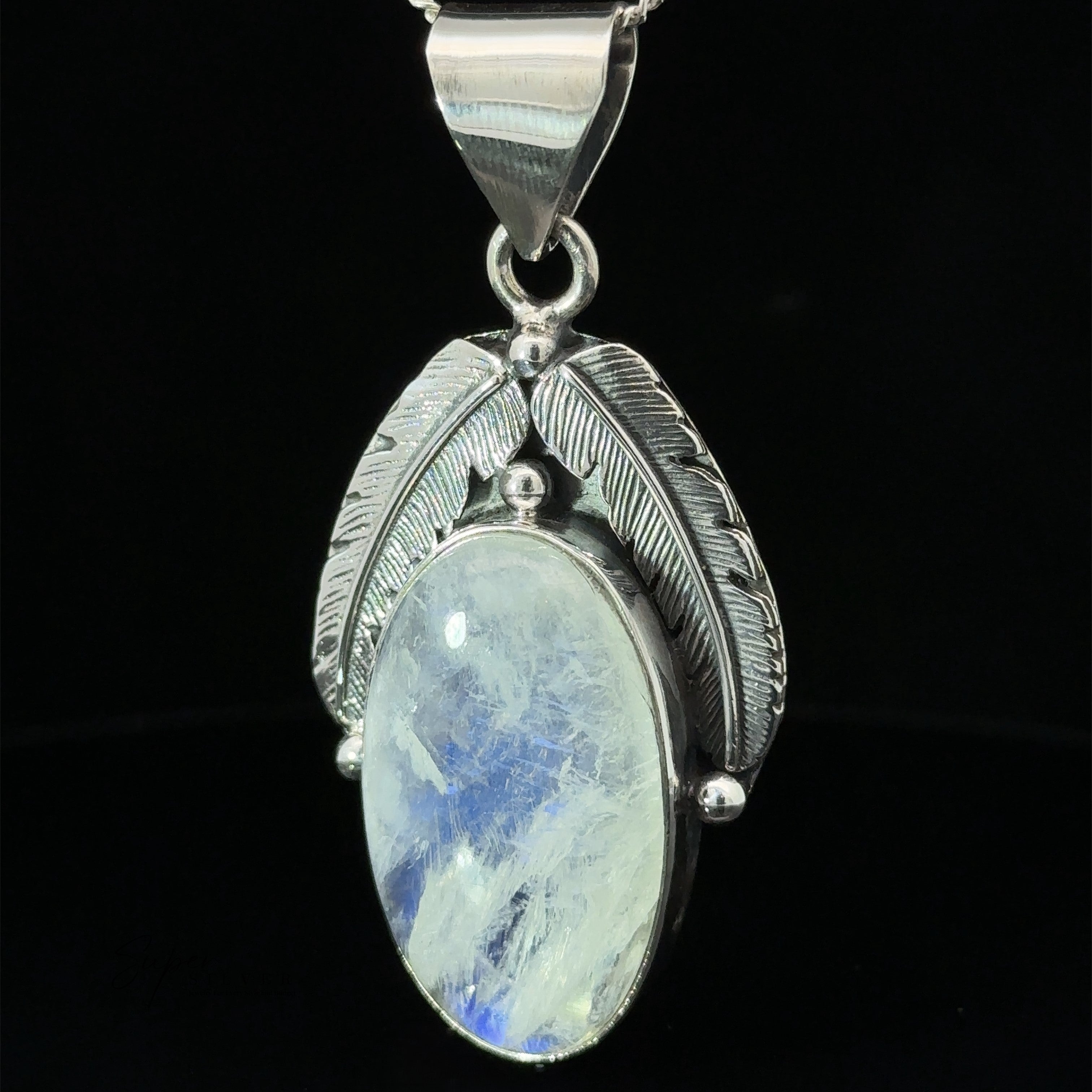 A Beautiful Southwest Stone Pendant featuring an oval moonstone set in silver with two detailed feather designs on either side, hanging from a silver chain.