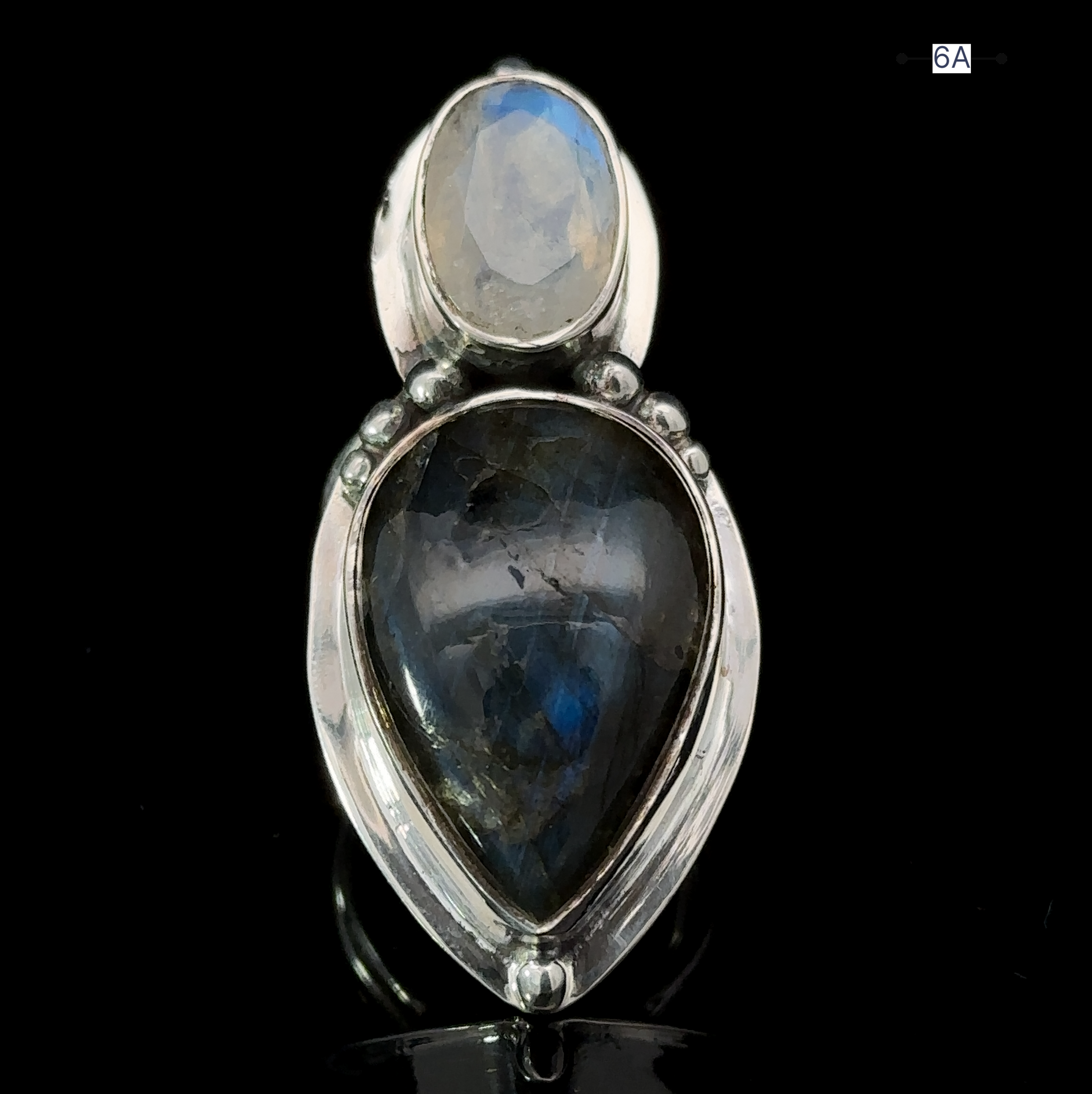 The Heavy Labradorite And Moonstone Ring is a stunning statement piece, featuring a captivating teardrop-shaped dark blue labradorite gemstone set below a smaller, round light blue moonstone.