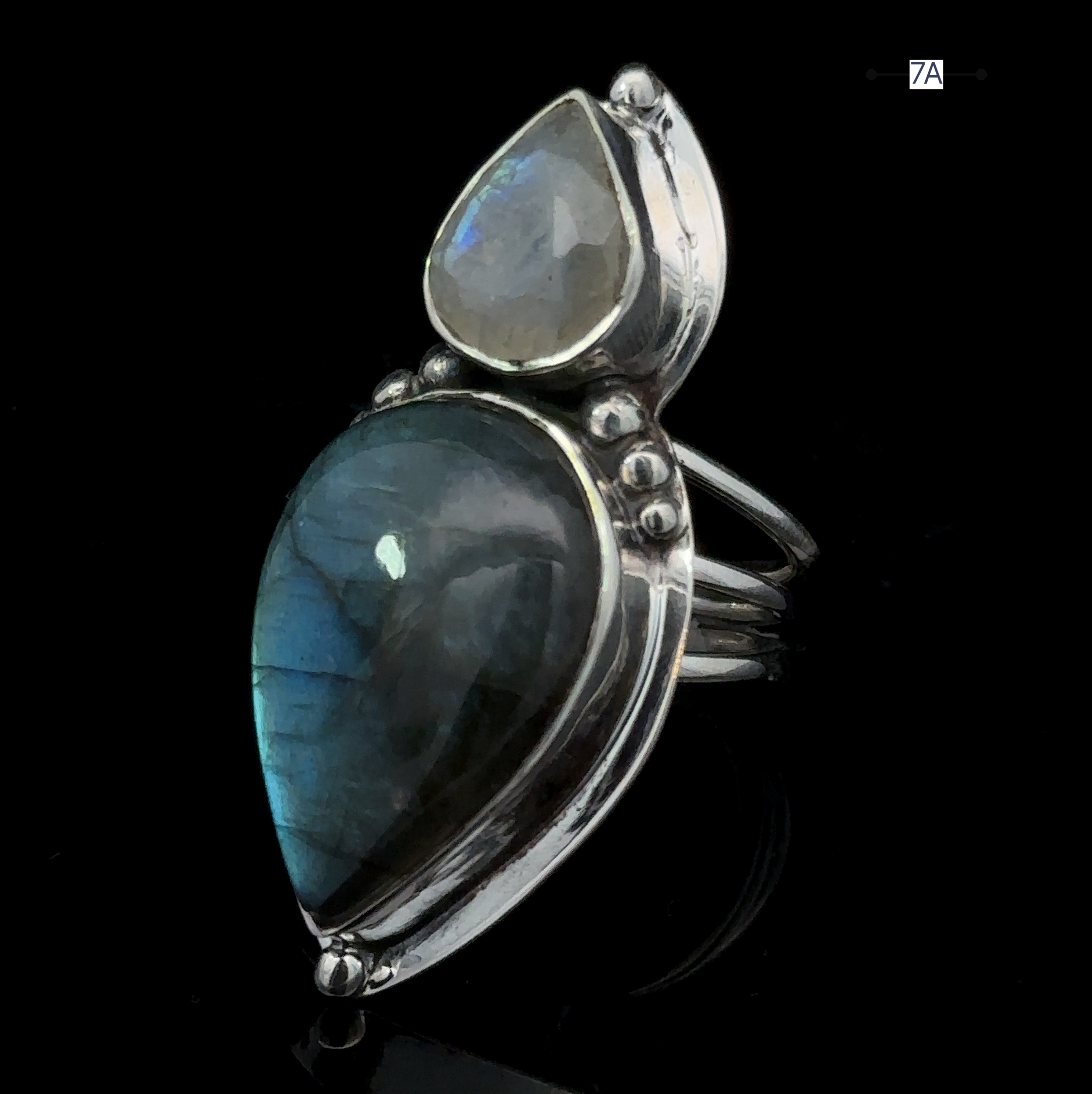 Heavy Labradorite and Moonstone Ring featuring a large labradorite and a smaller moonstone in teardrop shapes, set vertically and displayed on a black background.