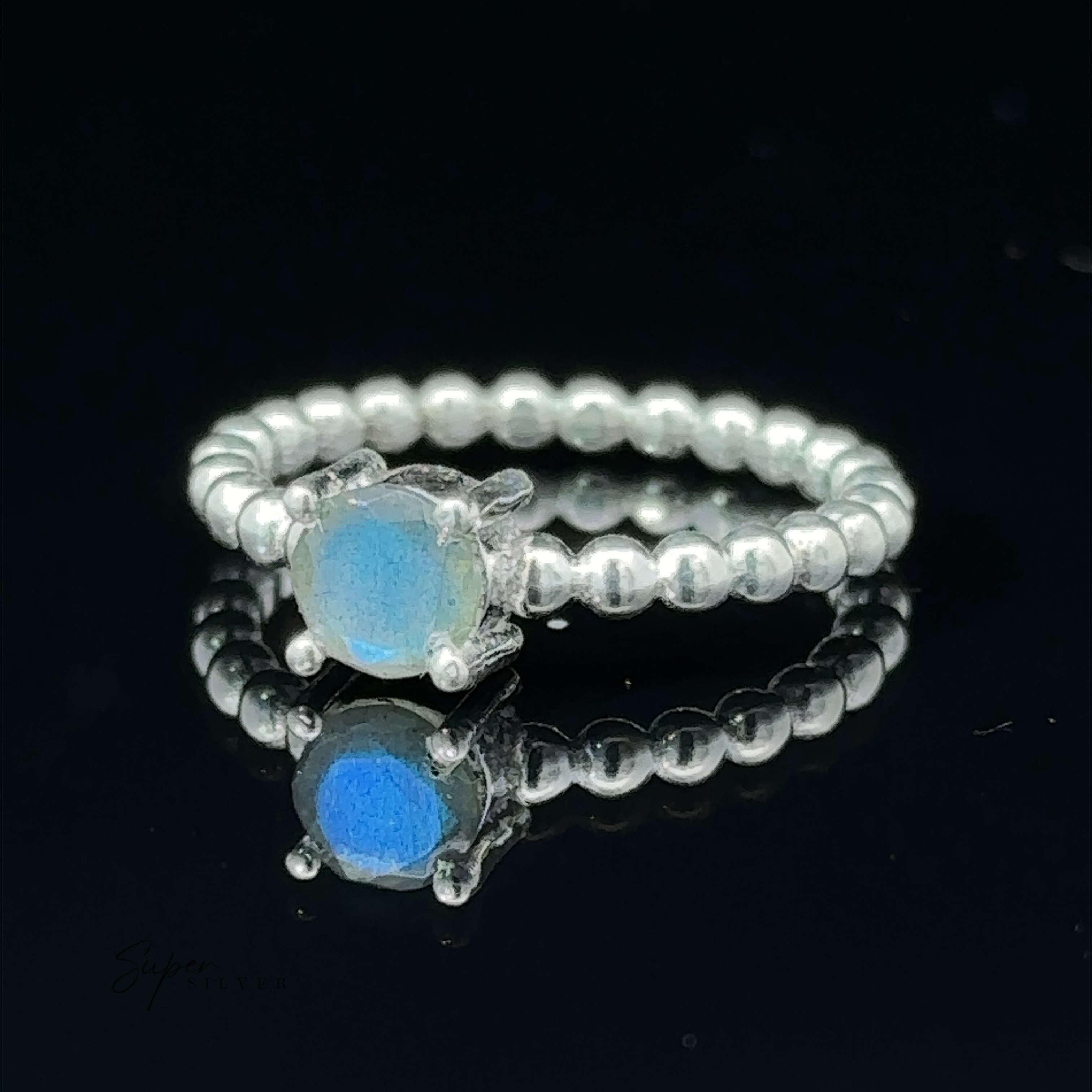 A stunning circular gemstone ring with a solitary vibrant blue gemstone, displayed on a reflective surface.