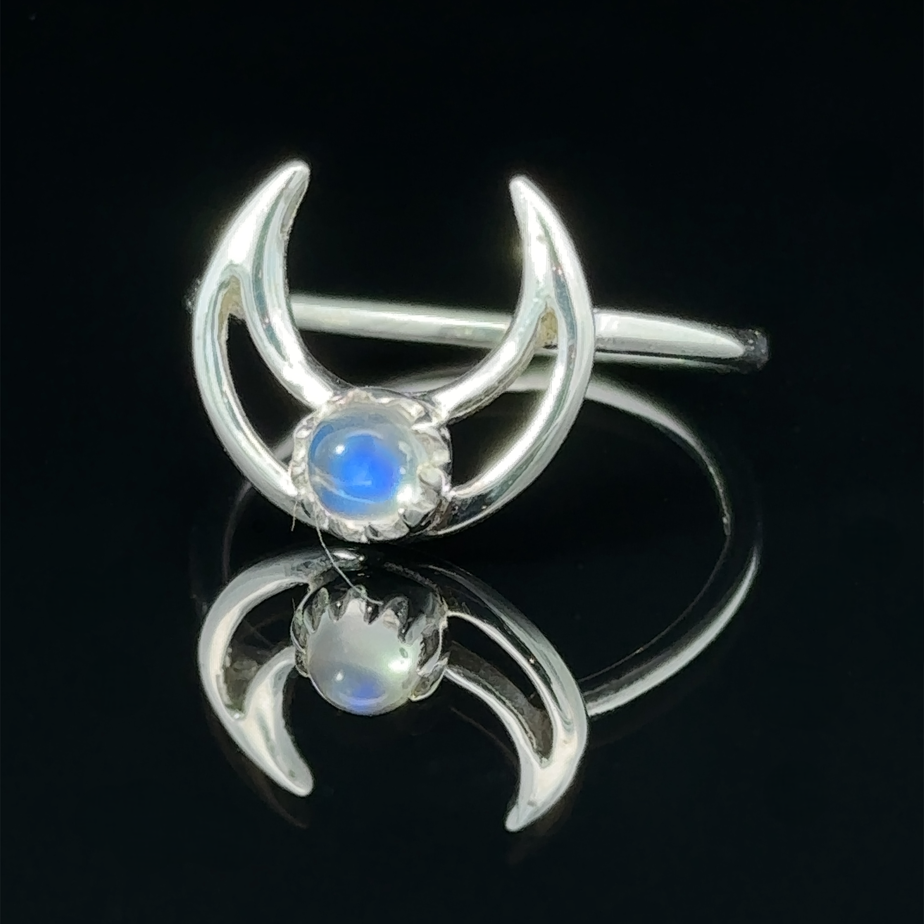 Online Exclusive Gemstone Moon Outline Ring with a moonstone center, reflected on a black surface.