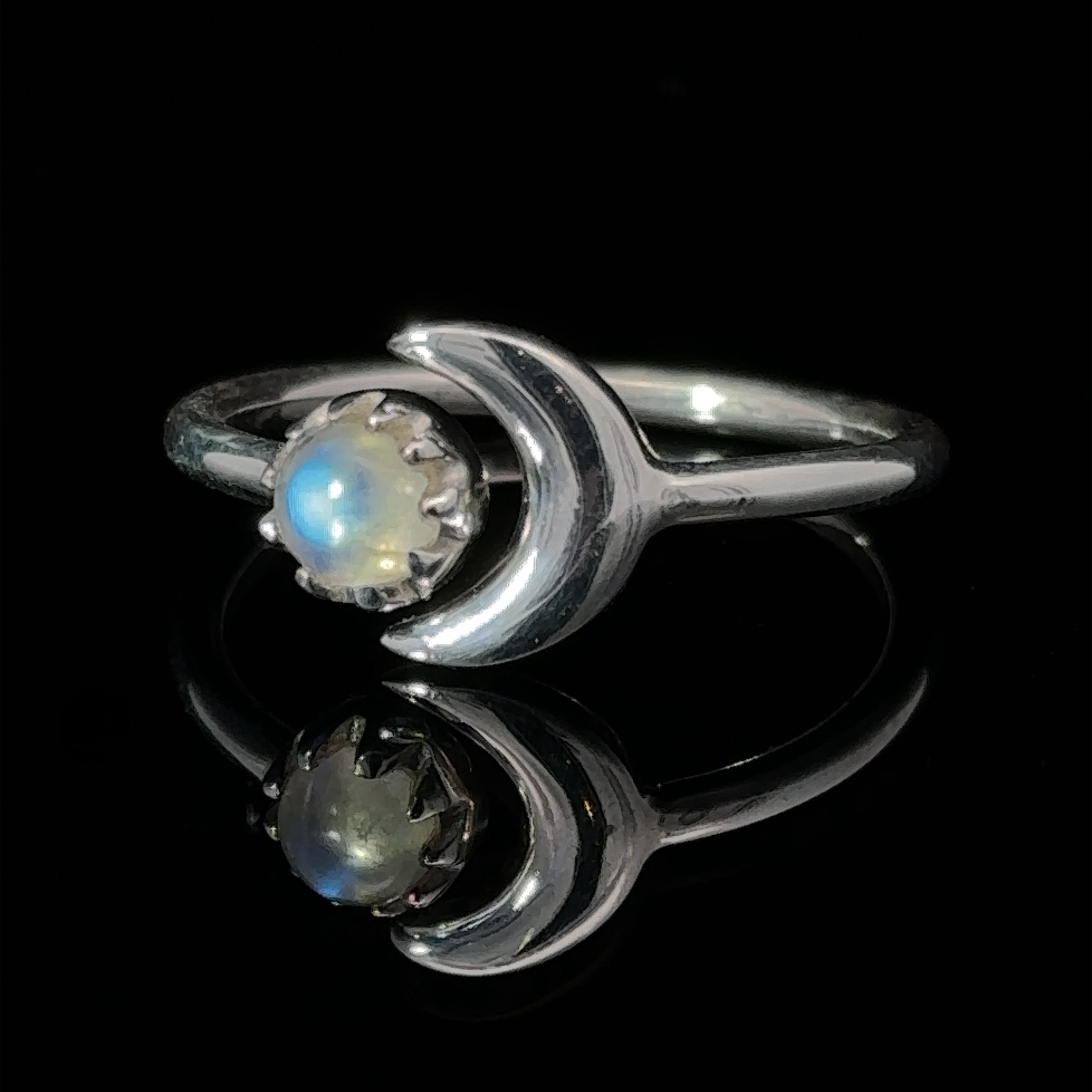 Online Exclusive Adjustable Gemstone Ring With Moon Design with a single opal stone, displayed on a reflective black surface.