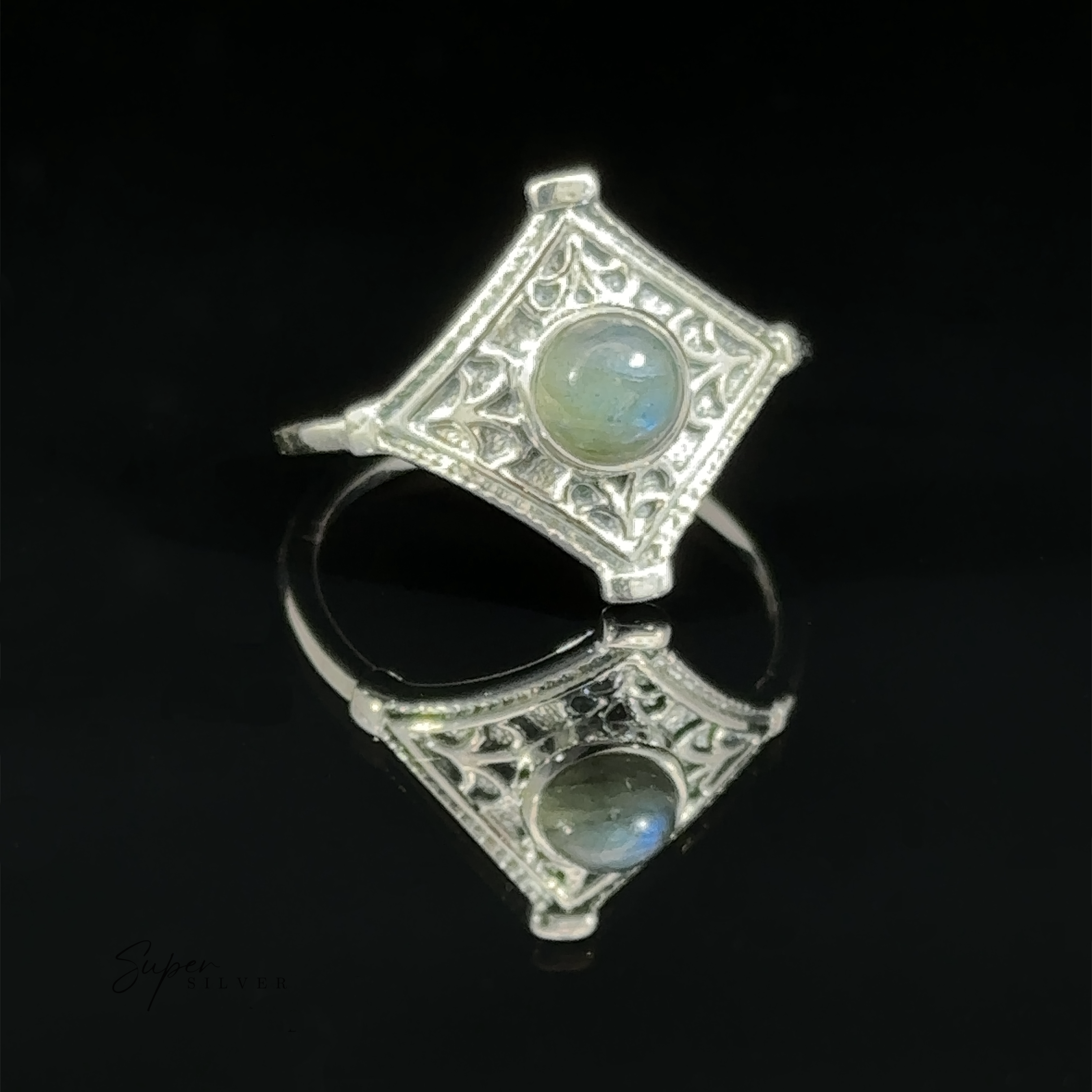 Sentence with product name: Intricate Diamond Silver Ring with a Round Moonstone set against a reflective black background.