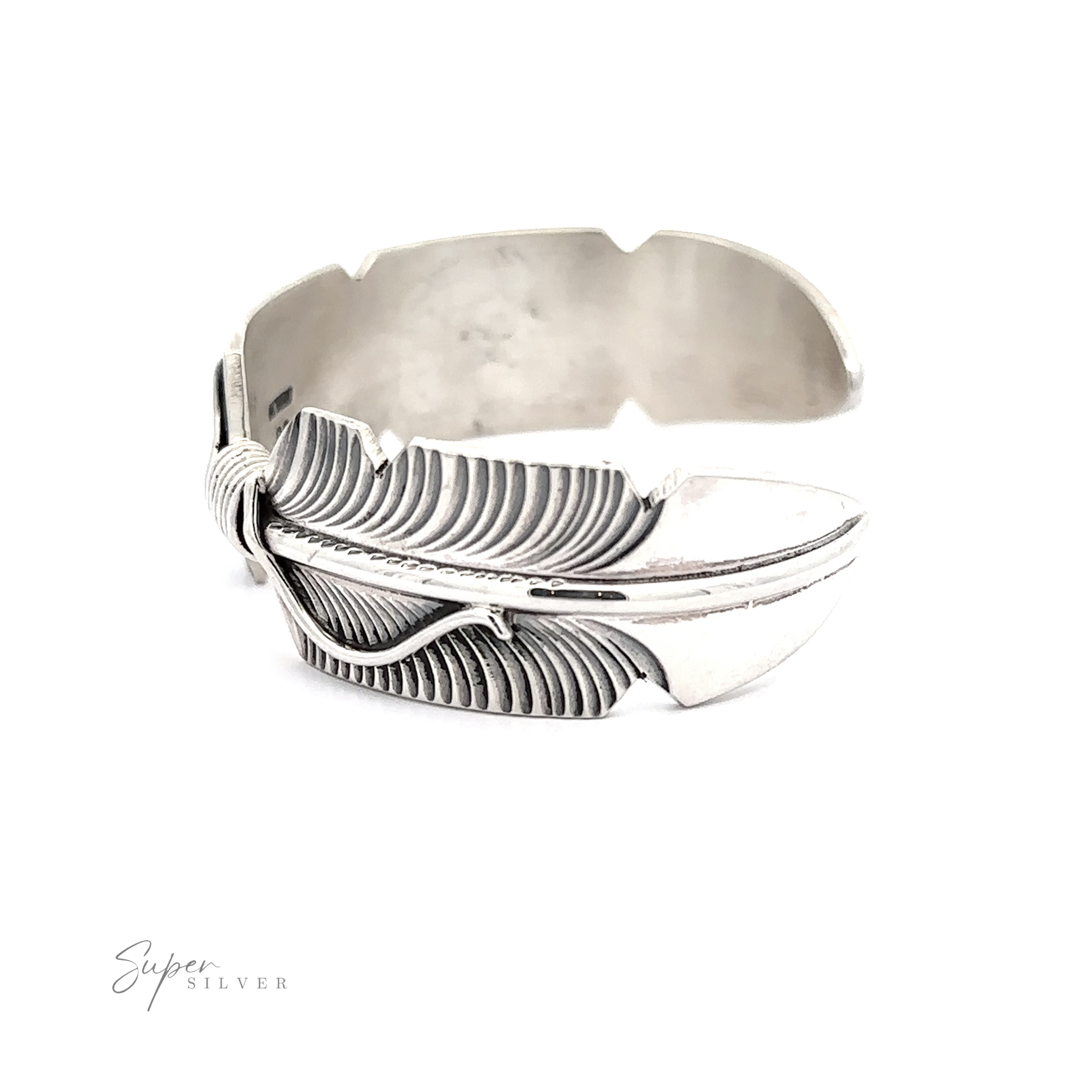 A Native American silver feather cuff bracelet displayed on a white background with a reflective surface.