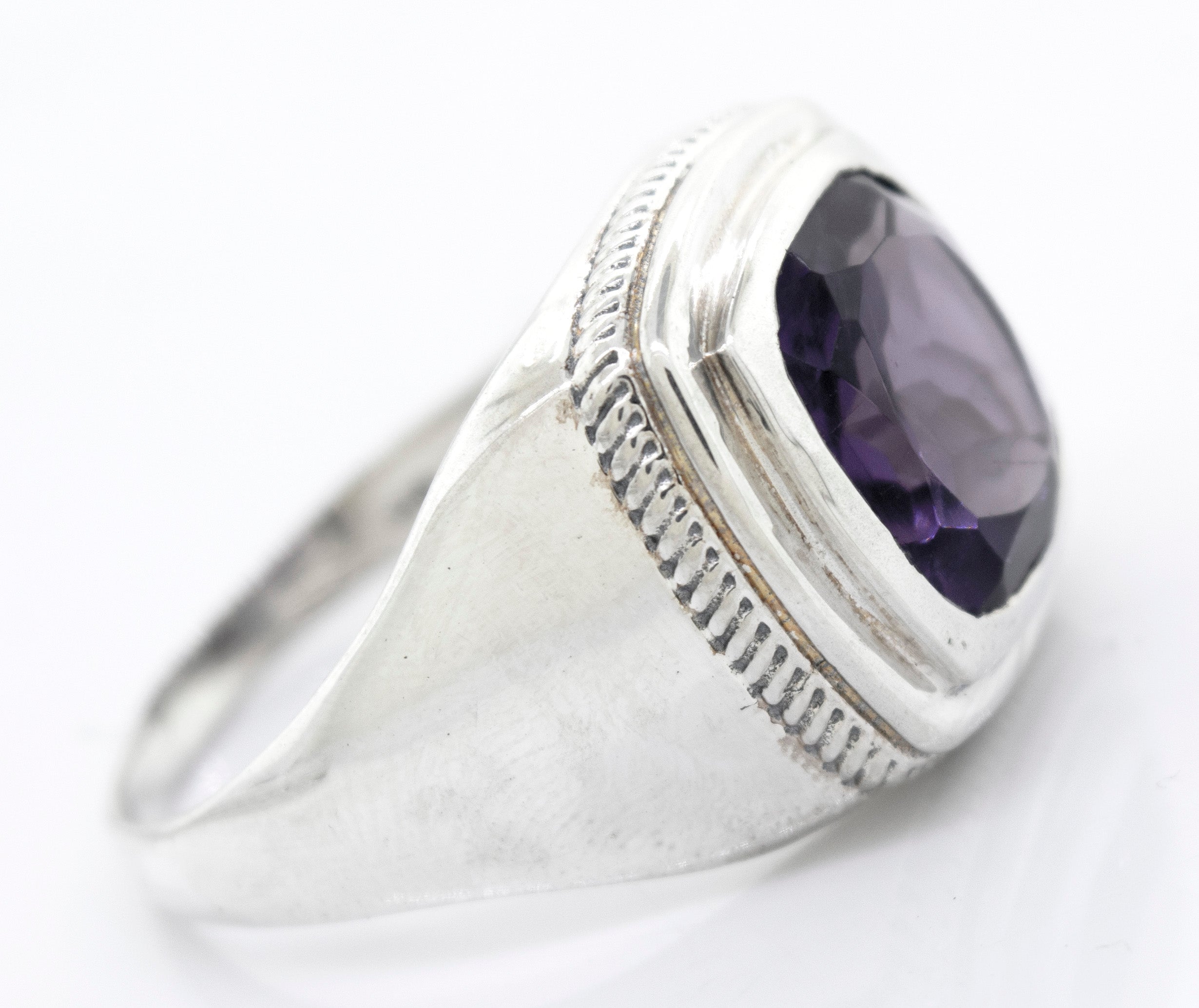 A Faceted Stone Signet Ring with a large oval-shaped amethyst gemstone set in a raised bezel on a white background.
