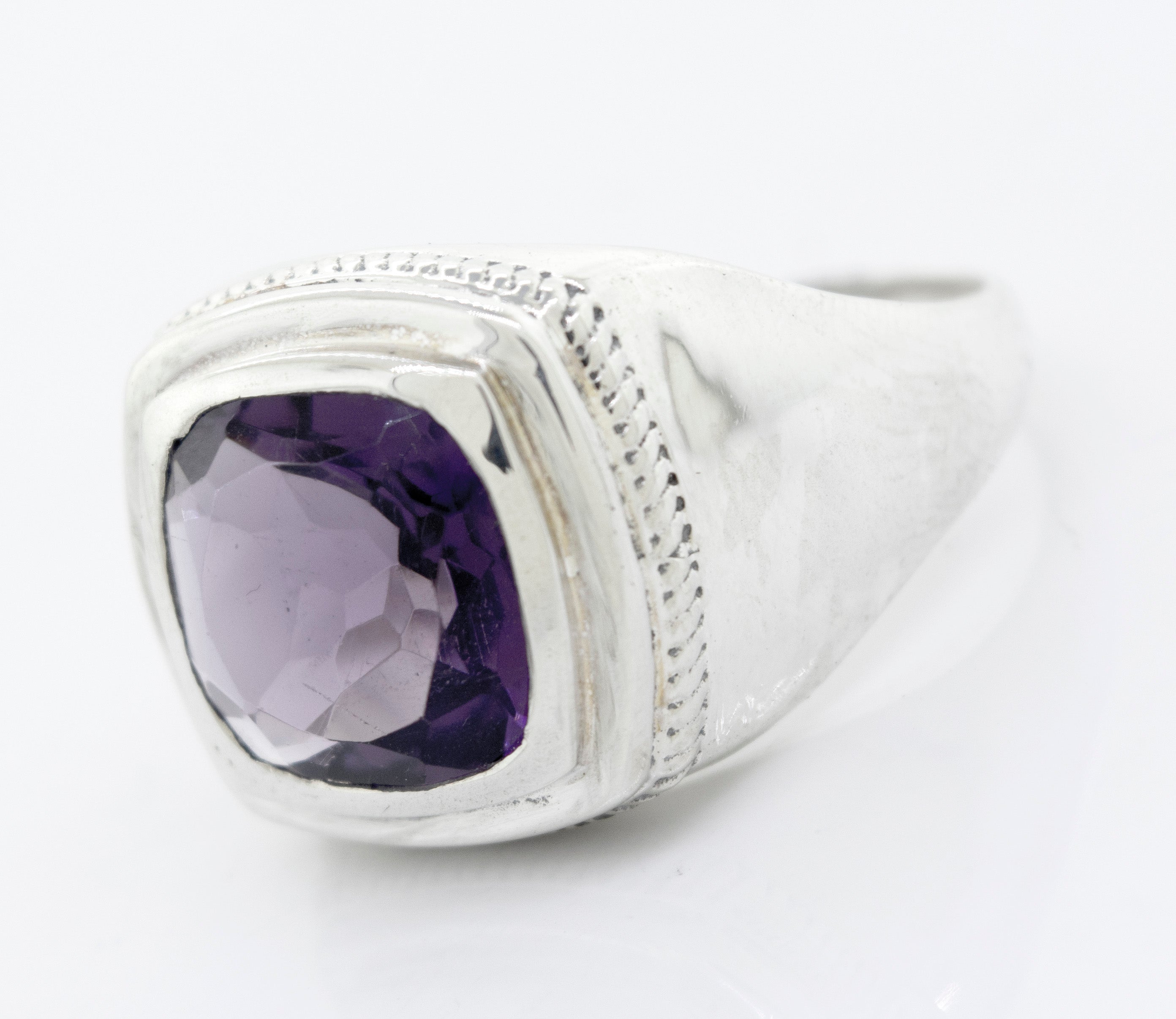 A Faceted Stone Signet Ring with an inset square amethyst gemstone, featuring a polished band and a textured border around the stone.