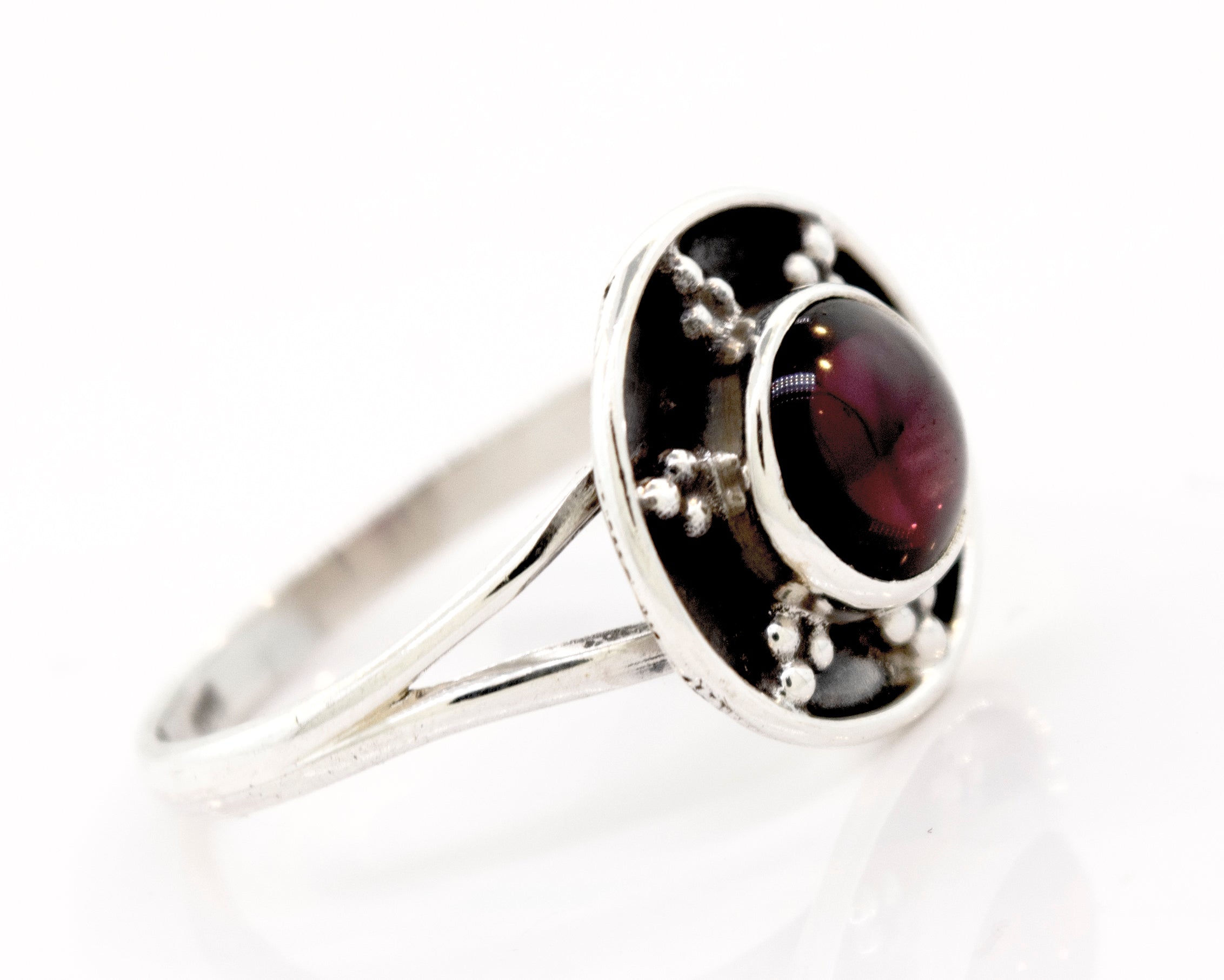 A **Gemstone Ring With Unique Oxidized Design** with a round, deep red gemstone set in the center, featuring small decorative silver beads around the stone. This exquisite piece of gemstone jewelry radiates elegance and timeless charm.