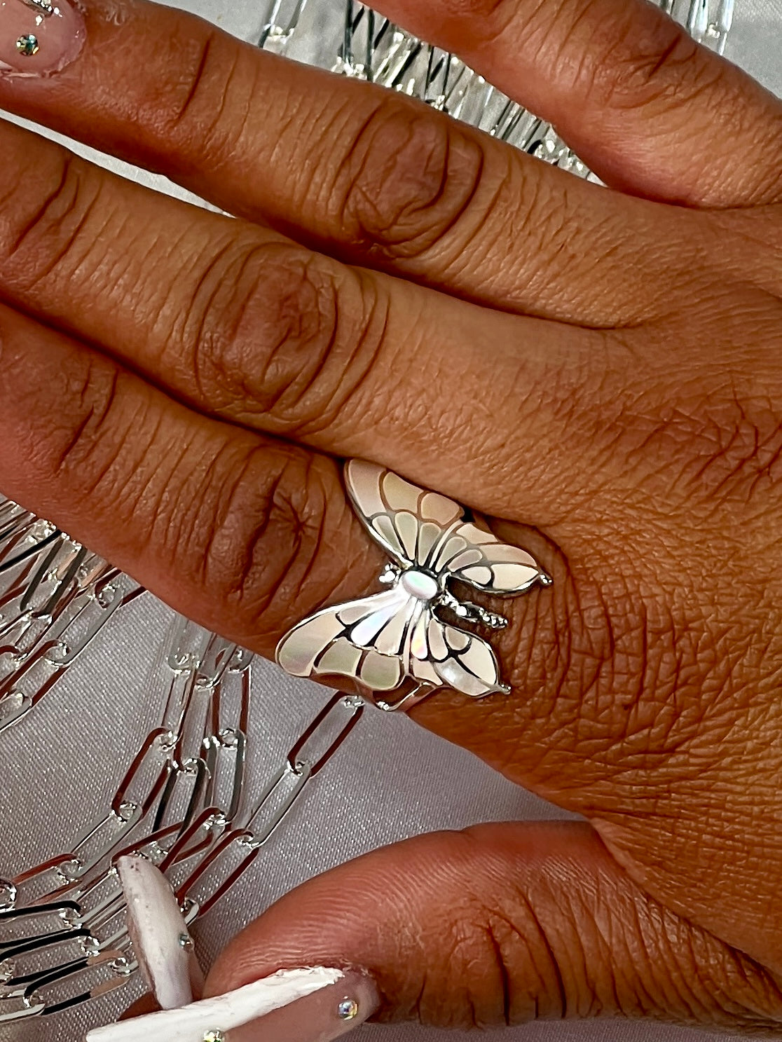 A woman's hand showcasing a stunning Super Silver Intricate Statement Butterfly Inlay Ring, creating a mesmerizing statement piece.