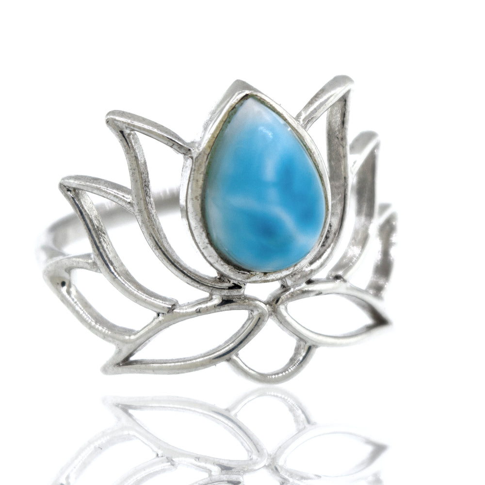 
                  
                    Online Exclusive Teardrop Stone Lotus Ring shaped like a lotus with a blue gemstone in the center, displayed against a white background with reflection.
                  
                