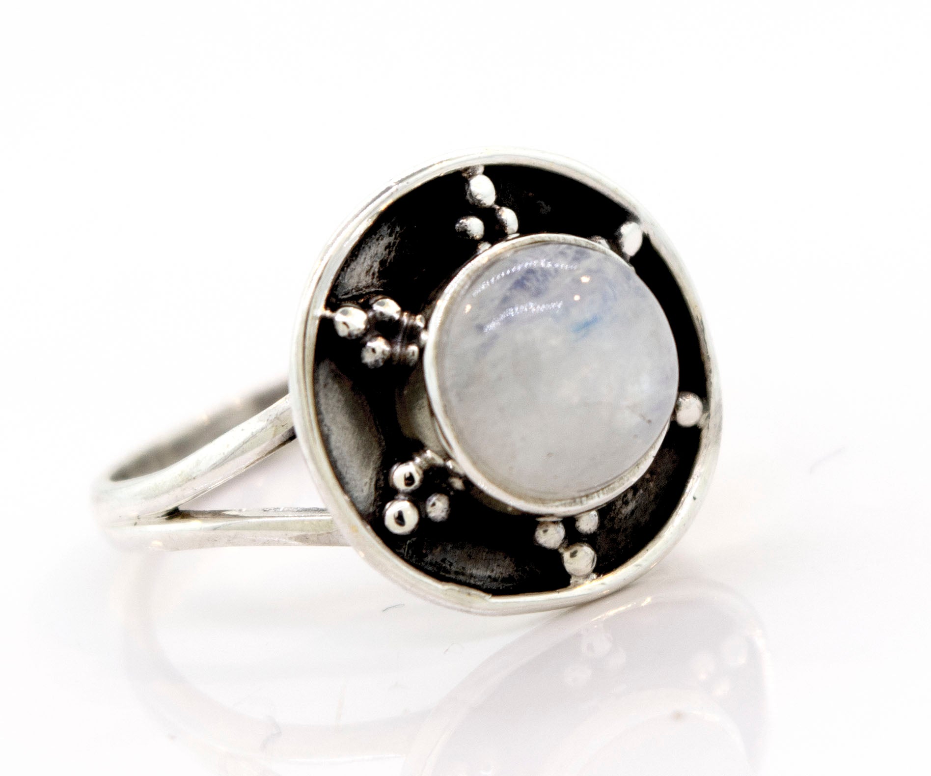 A Gemstone Ring With Unique Oxidized Design featuring a round moonstone set in an oxidized silver base with small silver bead accents surrounding the stone.