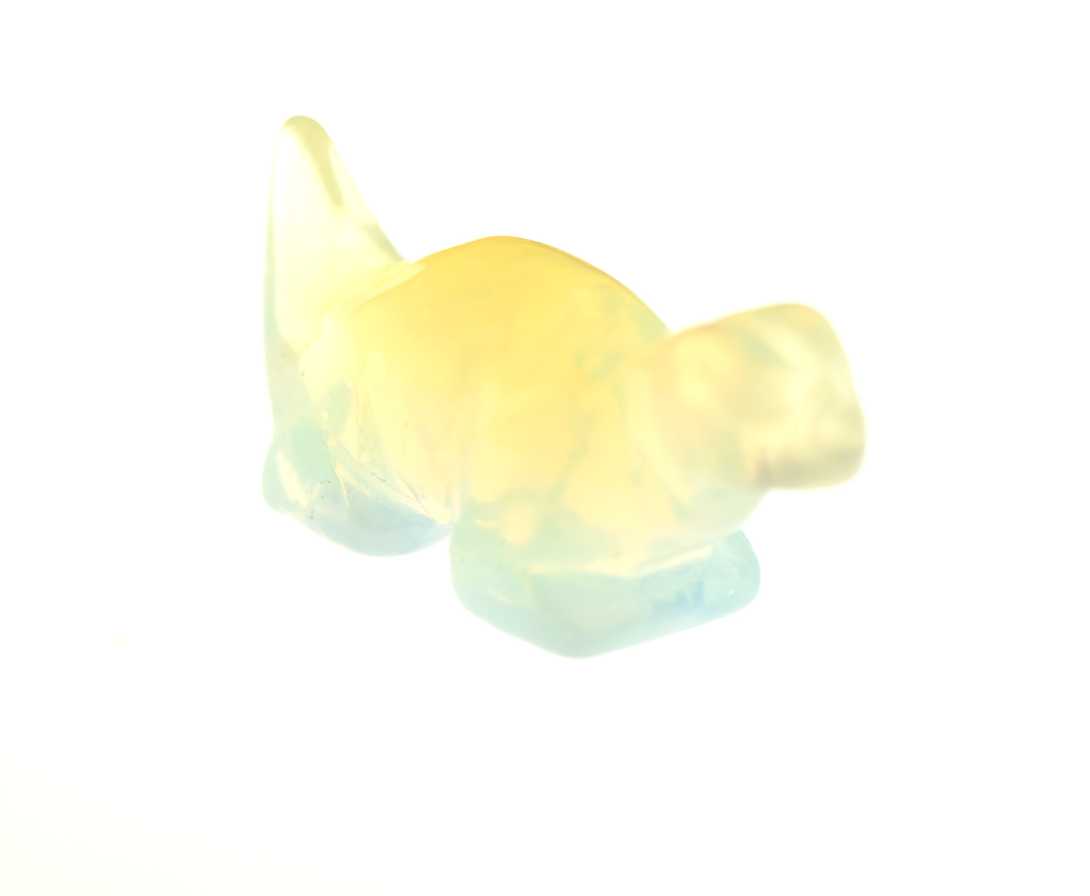 A small, translucent Carved Dinosaur Gemstone Figure in yellow and light blue colors against a white background.