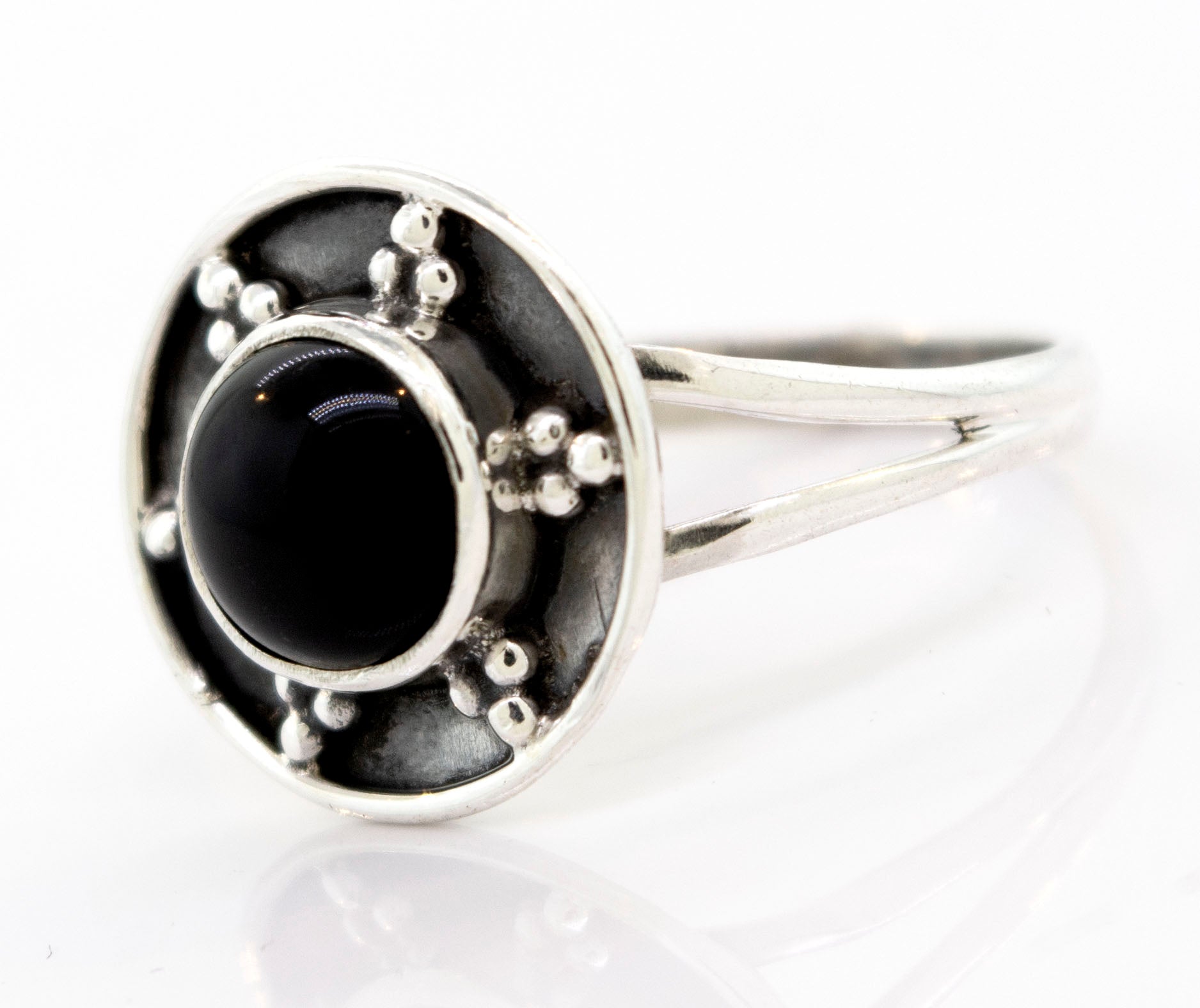 A Gemstone Ring With Unique Oxidized Design featuring a central black stone surrounded by a circular design with metal beads on a white background.