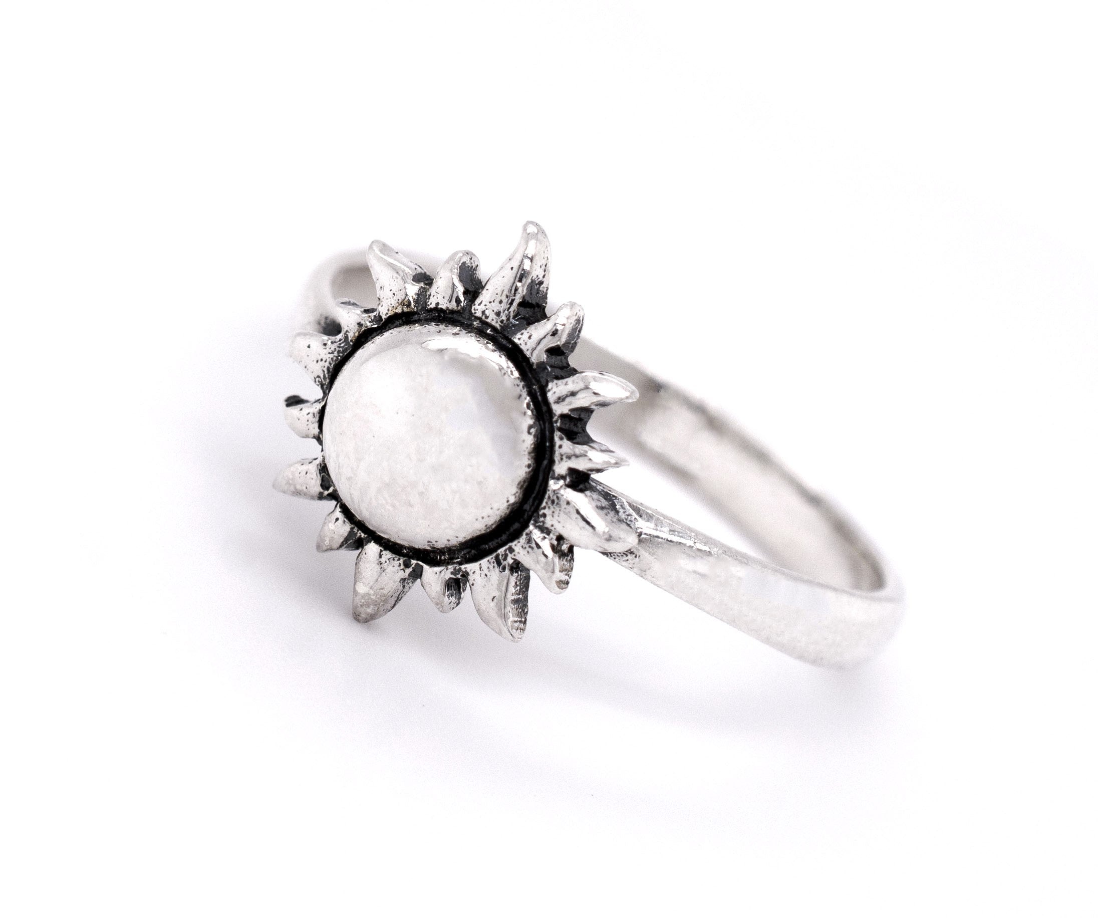 The Silver Sun Ring is a minimalist piece made from .925 Sterling Silver, featuring a sun-shaped design with a round, white stone in the center.