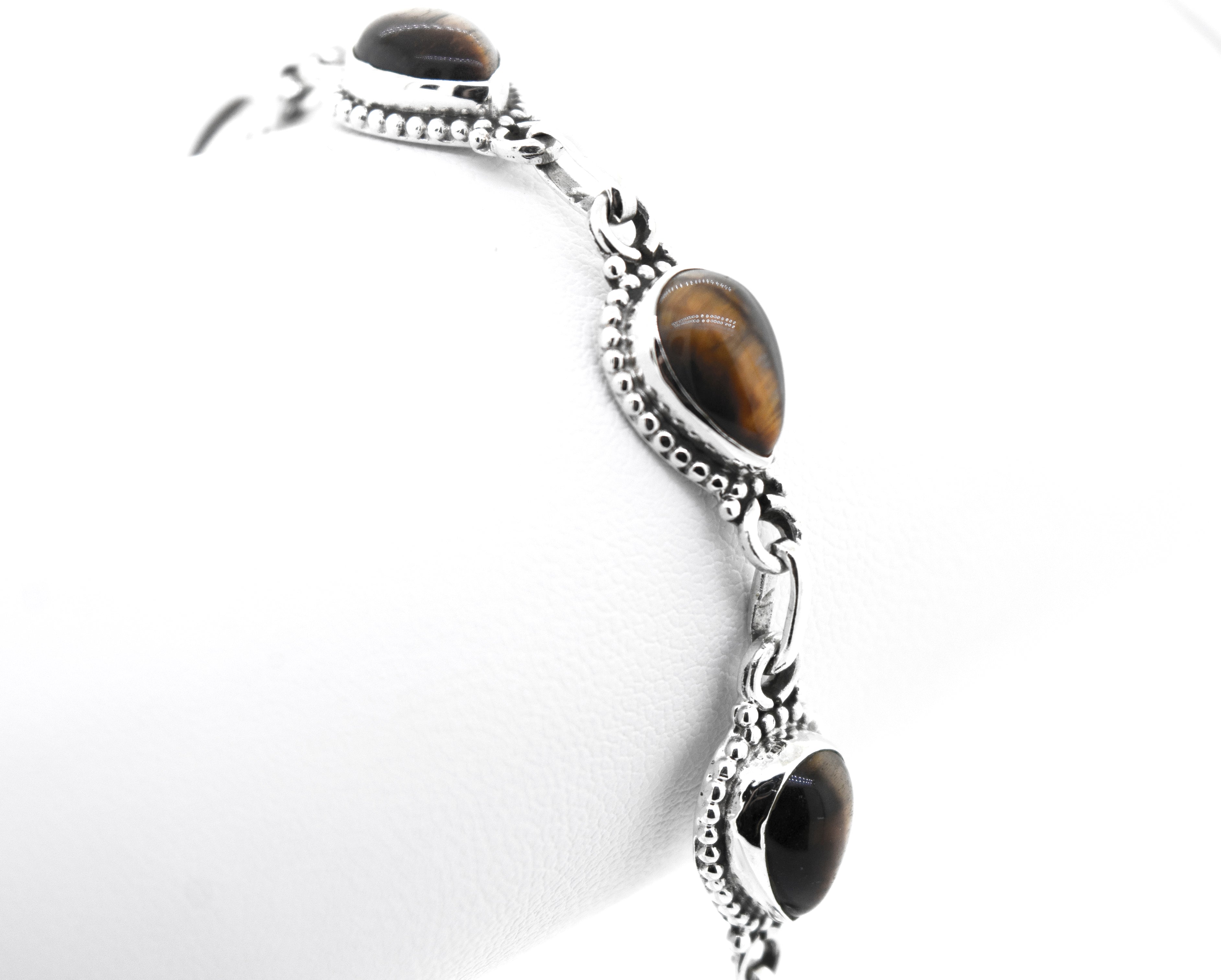 A close-up of a stunning Teardrop Shape Stone Bracelet With Ball Border featuring three tiger's eye gemstone settings on a plain white background.