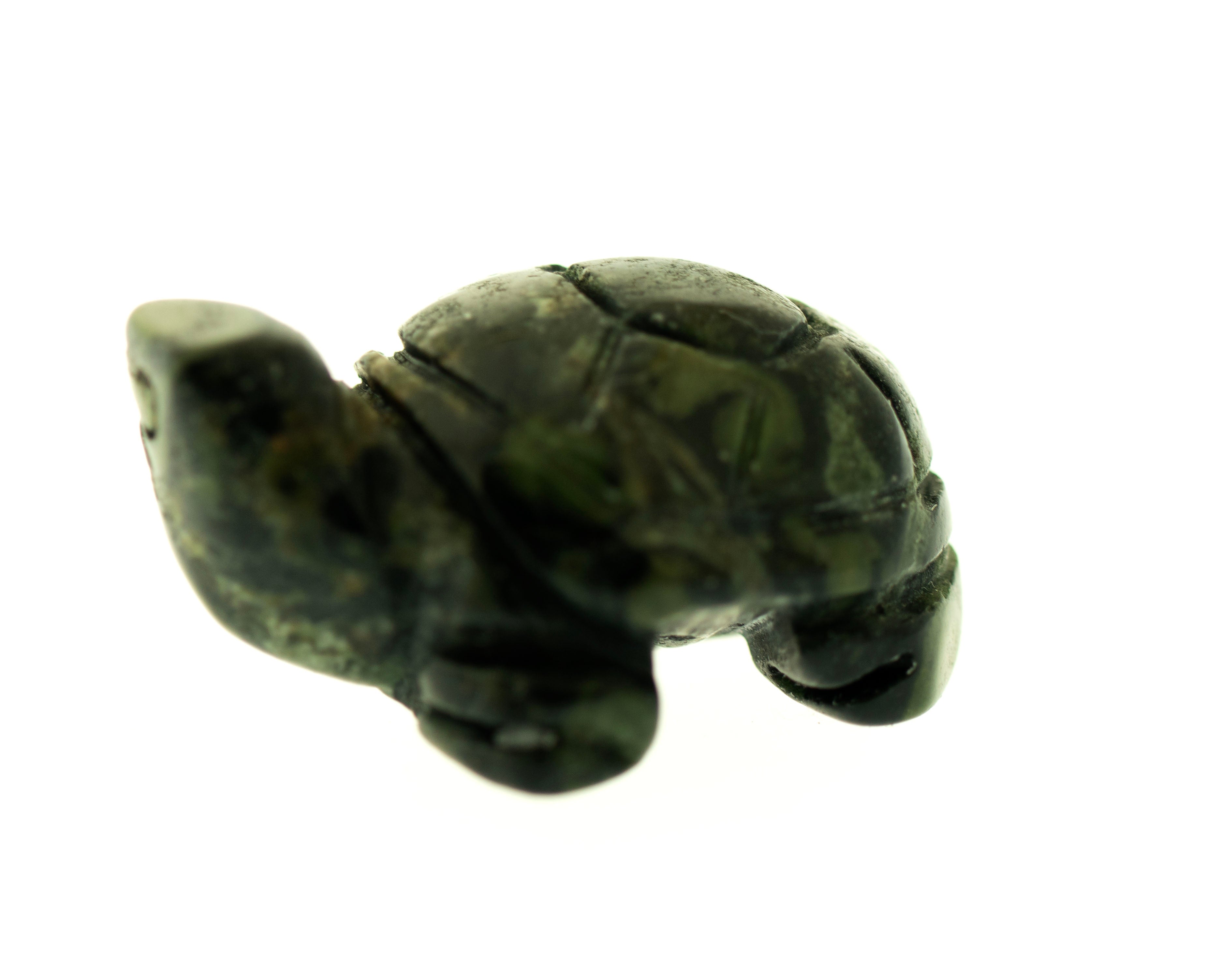 A small, dark green, carved turtle gemstone figure stands against a plain white background.