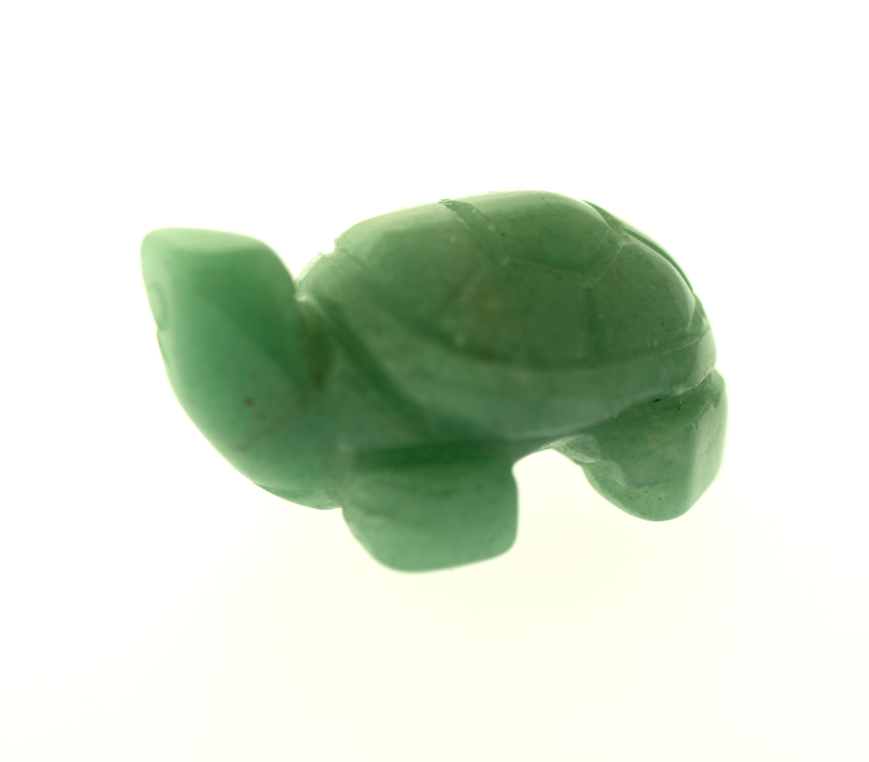 A small green turtle figurine made of jade, it stands among a collection of Carved Turtle Gemstone Figures, displayed on a plain white background.