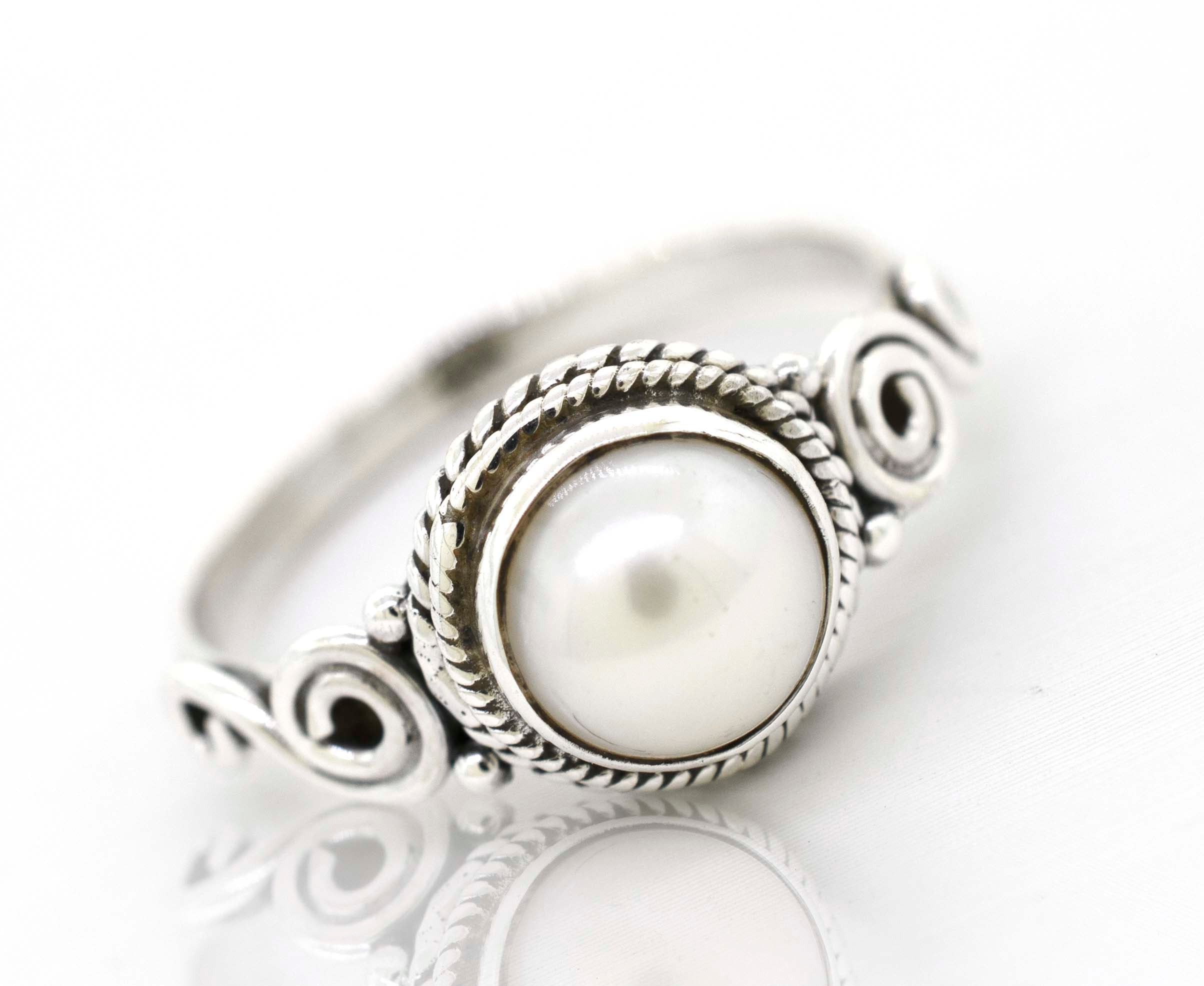 A gemstone circle ring with rope border and swirl design.