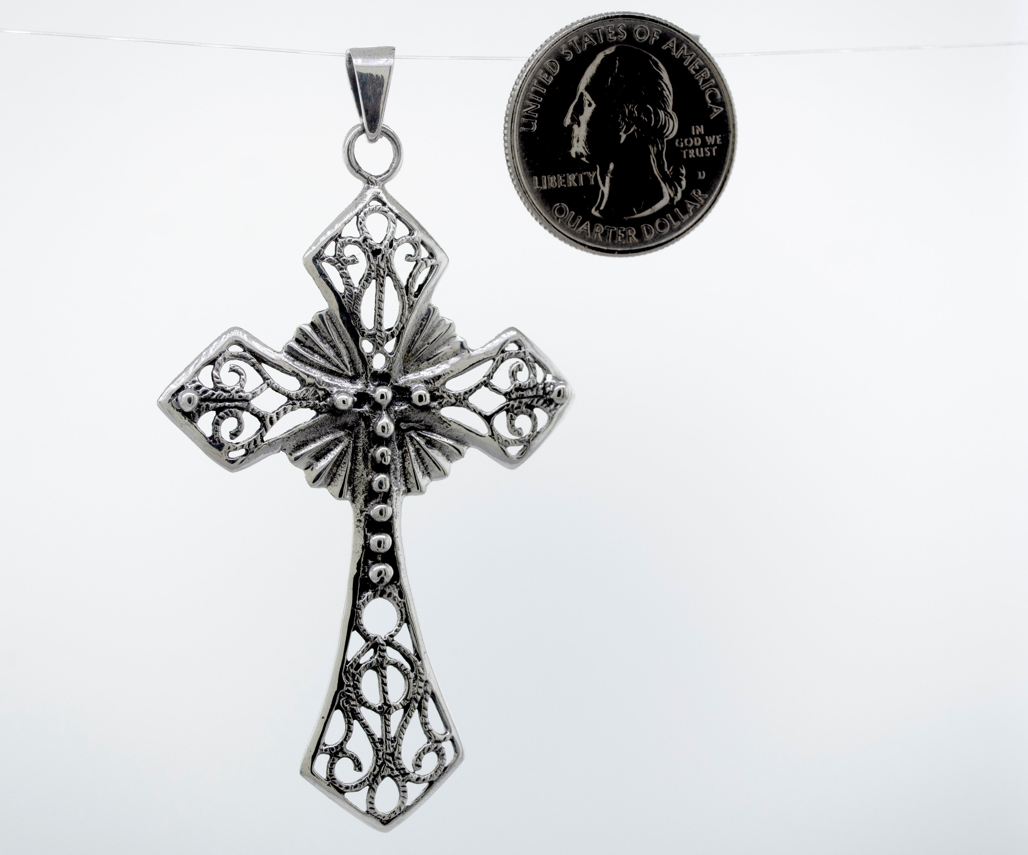 A unique Super Silver Ornate Cross Pendant adorned with intricate silverwork, showcased alongside a dime.