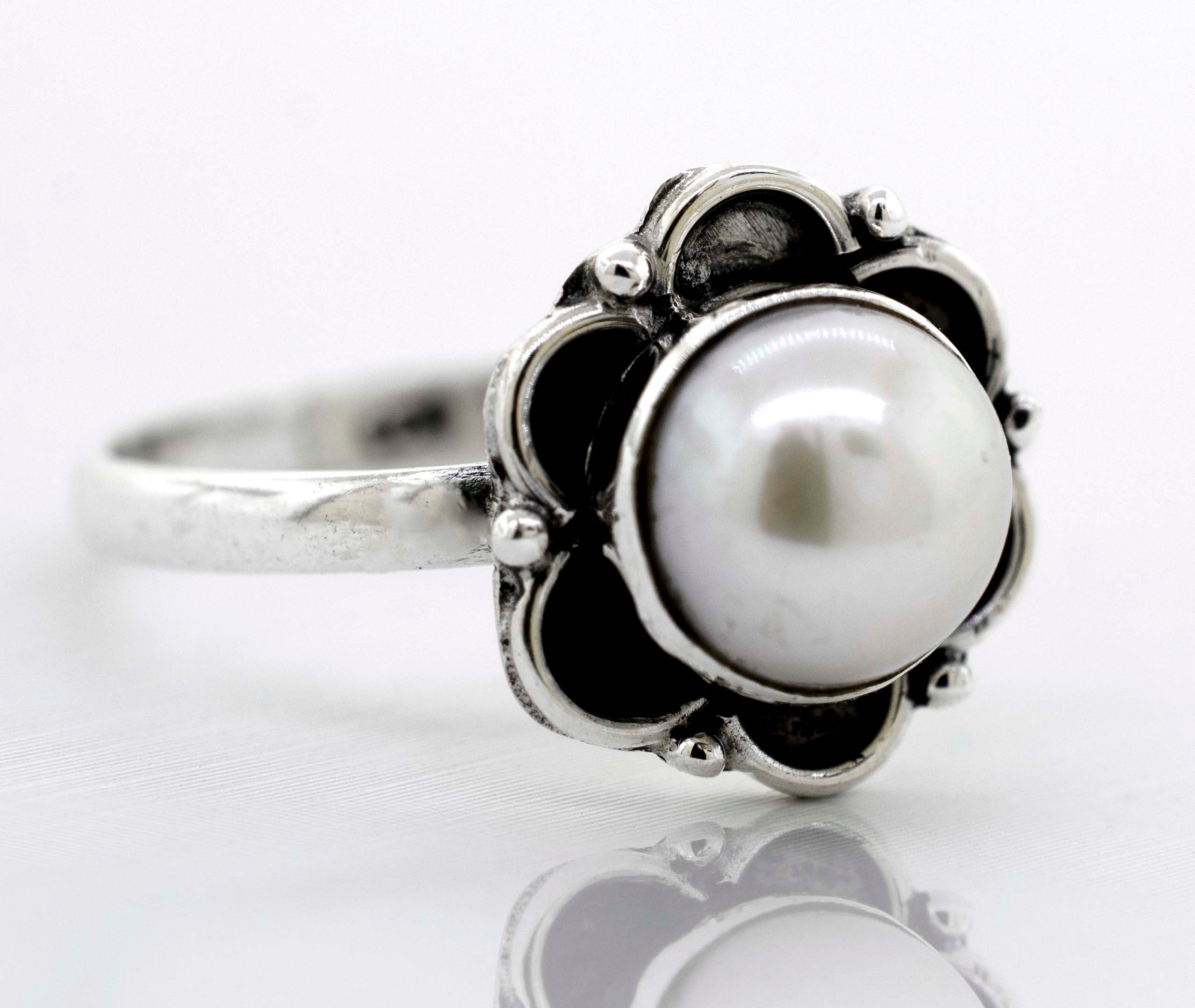 A delicate Super Silver Gemstone Ring With Oxidized Flower Design with a central gemstone placed on a white surface.