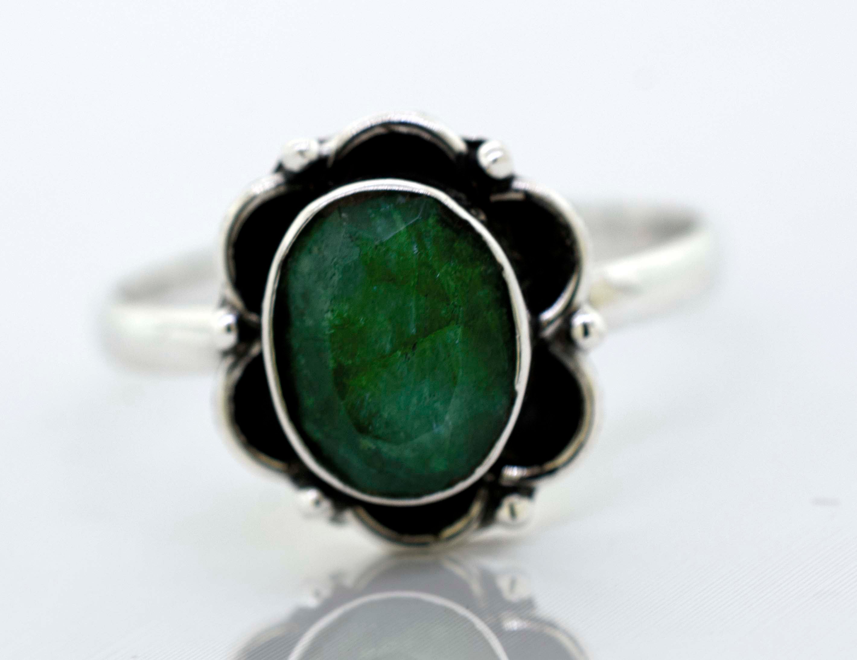 A delicate Super Silver Gemstone Ring With Oxidized Flower Design with a central green gemstone surrounded by black stones.