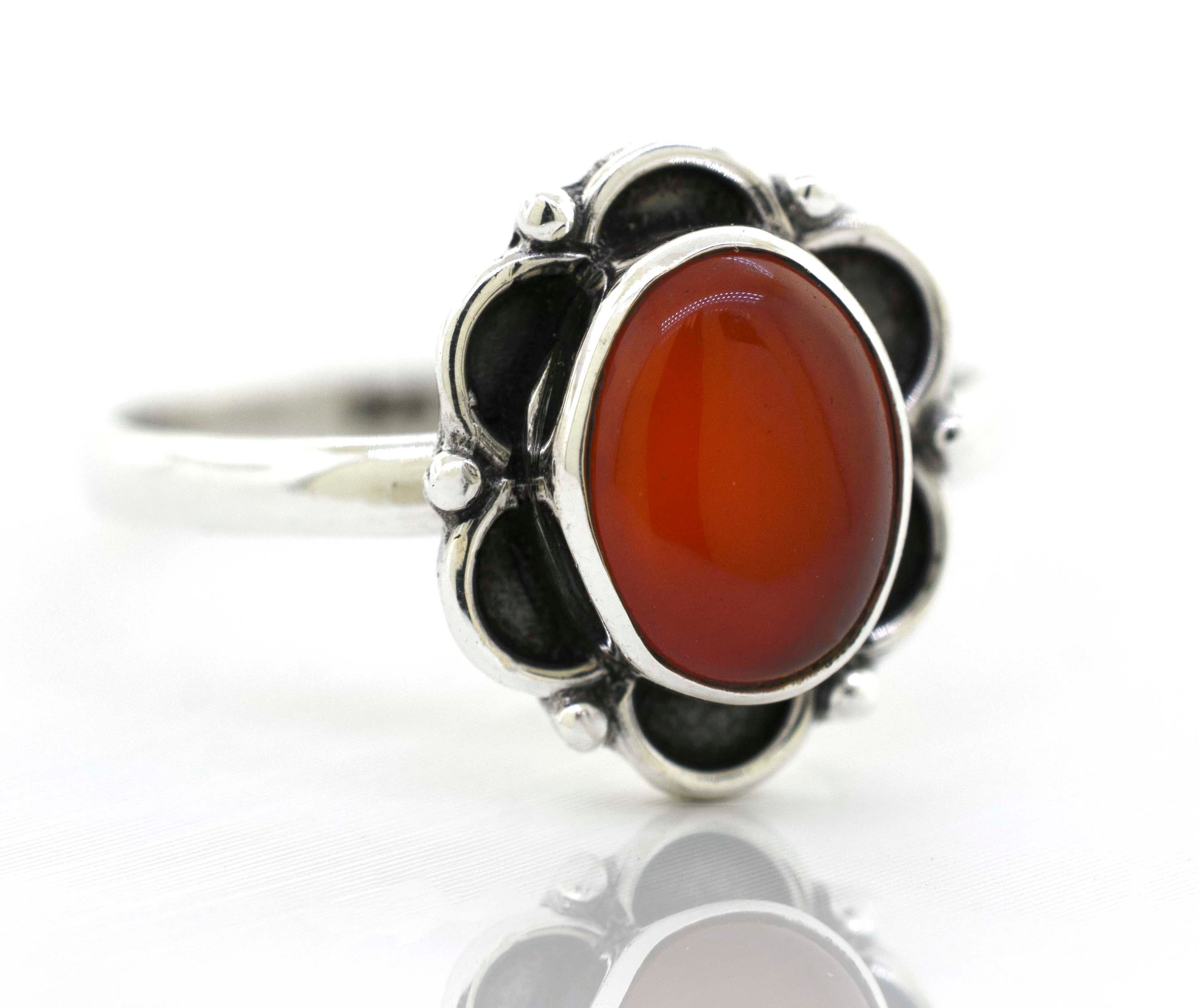 A delicate Super Silver gemstone ring with a central carnelian gemstone surrounded by delicate silver petals.