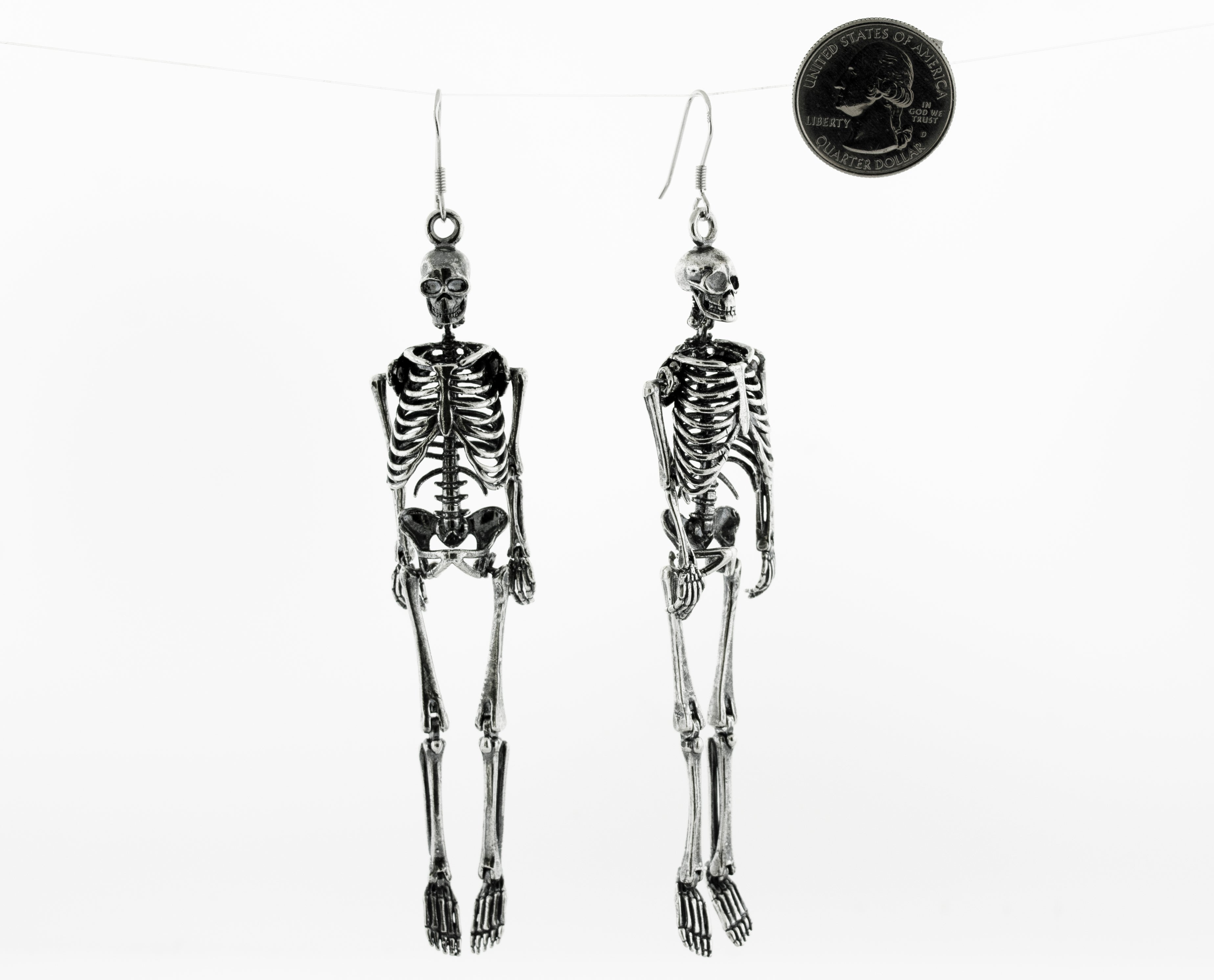 Two Super Silver sterling silver skeleton earrings, hanging on a string.