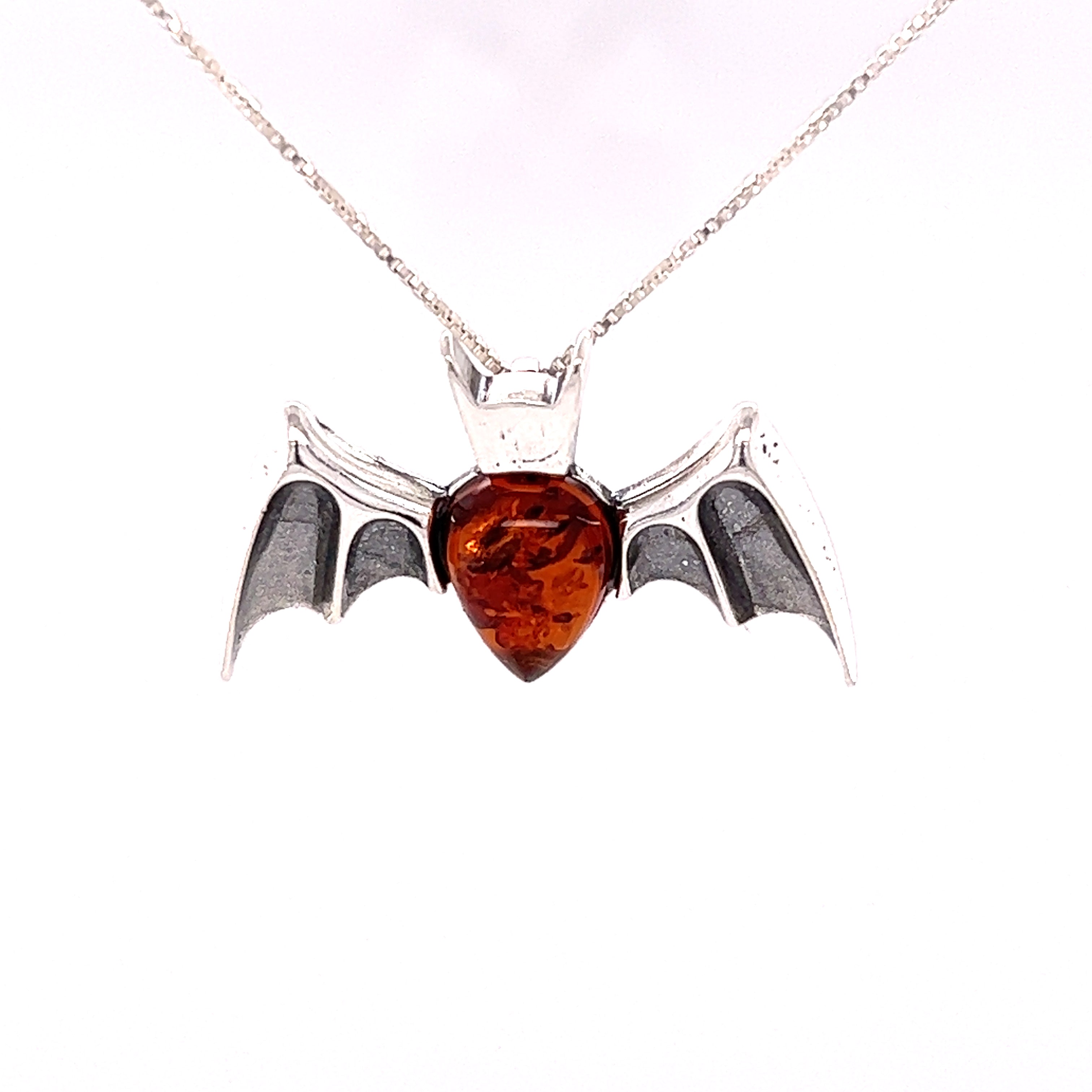 A Super Silver Haunting Amber Bat Pendant adorned with a vibrant red amber stone.