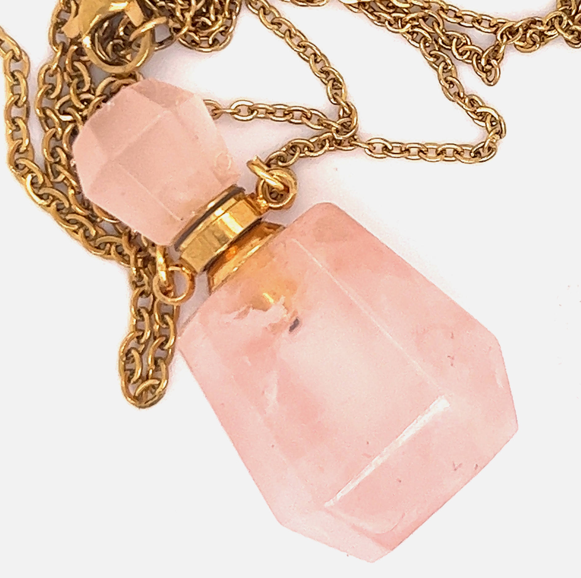 A Super Silver Crystal Perfume Vial Necklace adorned with a pink quartz stone, hanging delicately on a gold chain.
