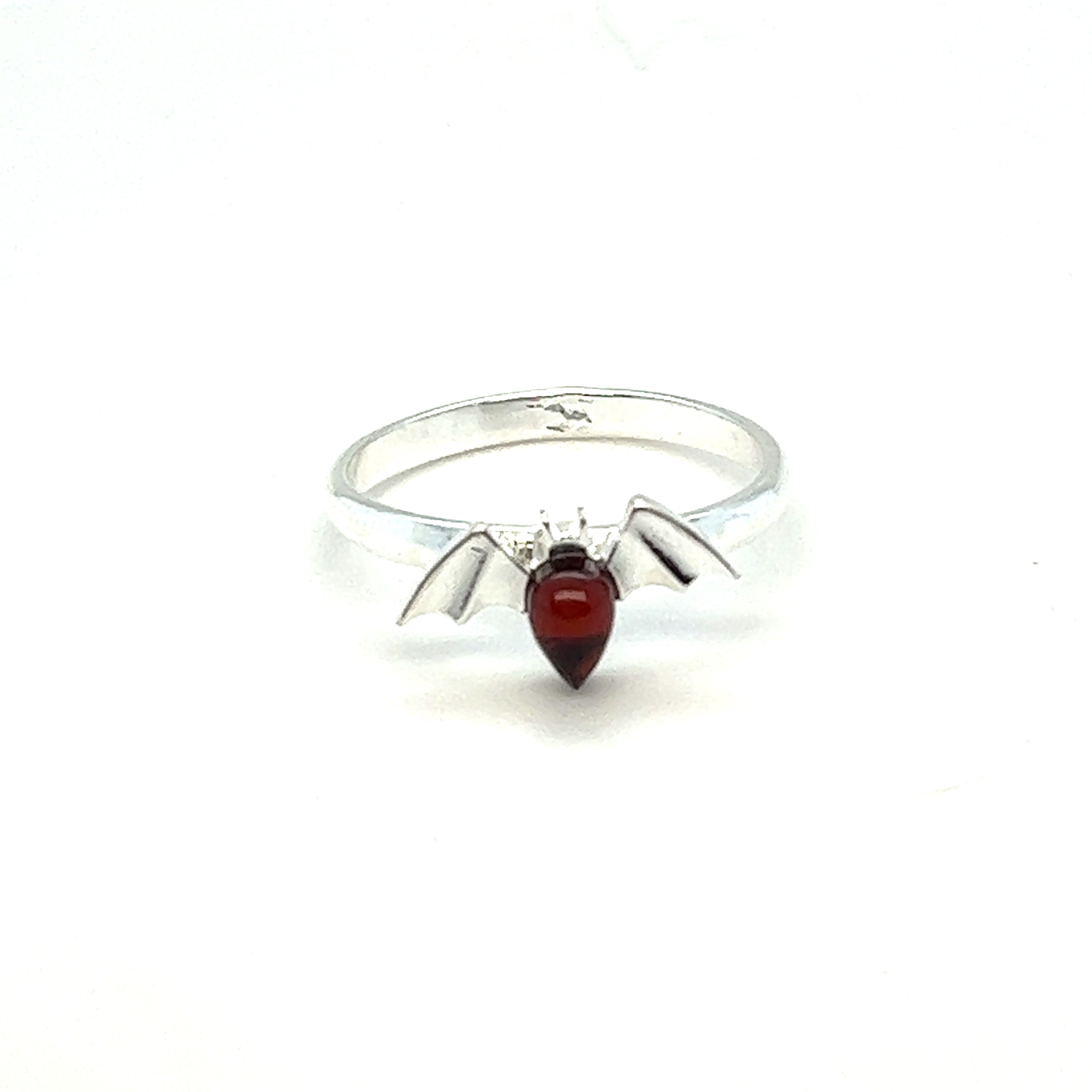 A Baltic Amber Bat Ring with a red garnet stone featuring witches, made by Super Silver.