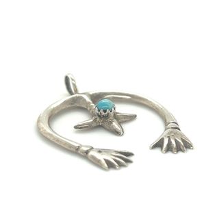 A Super Silver Native American Naja Pendant With Turquoise adorned with a turquoise stone.
