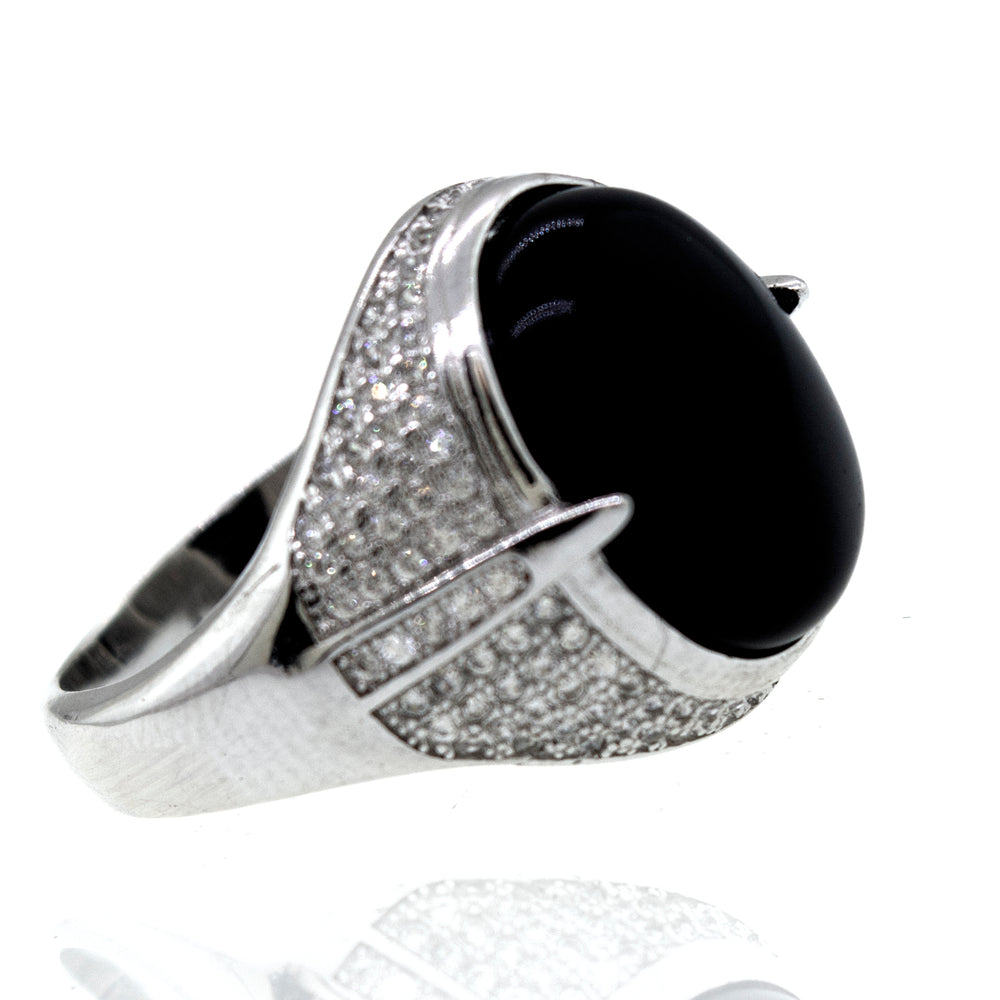 An elegant Super Silver ring featuring an oval Onyx And Cubic Zirconia stone, accentuated by shimmering diamonds, set on a pristine white background.