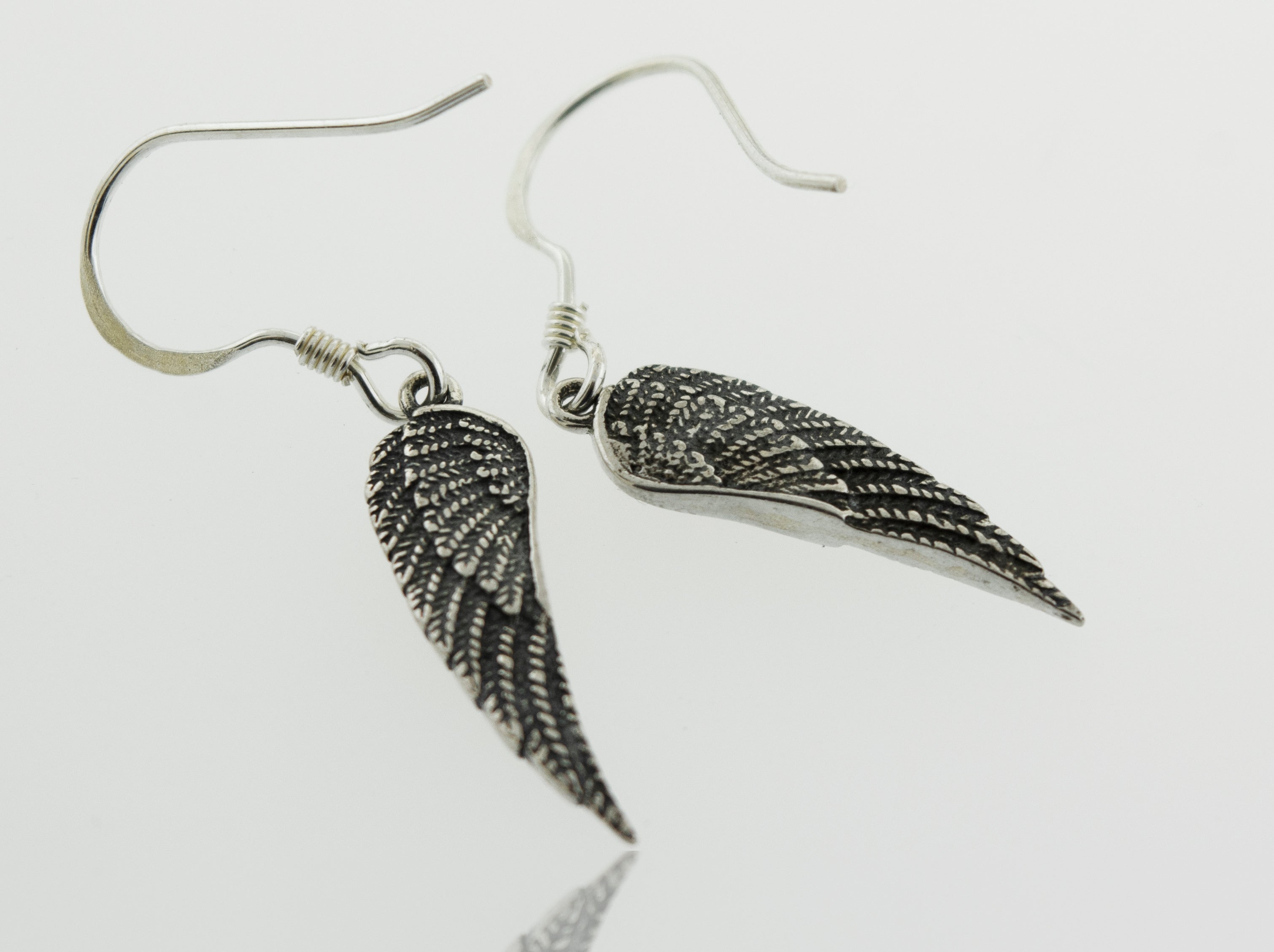 A pair of Super Silver Dainty Wing Earrings crafted from .925 sterling silver, displayed on a pristine white surface.