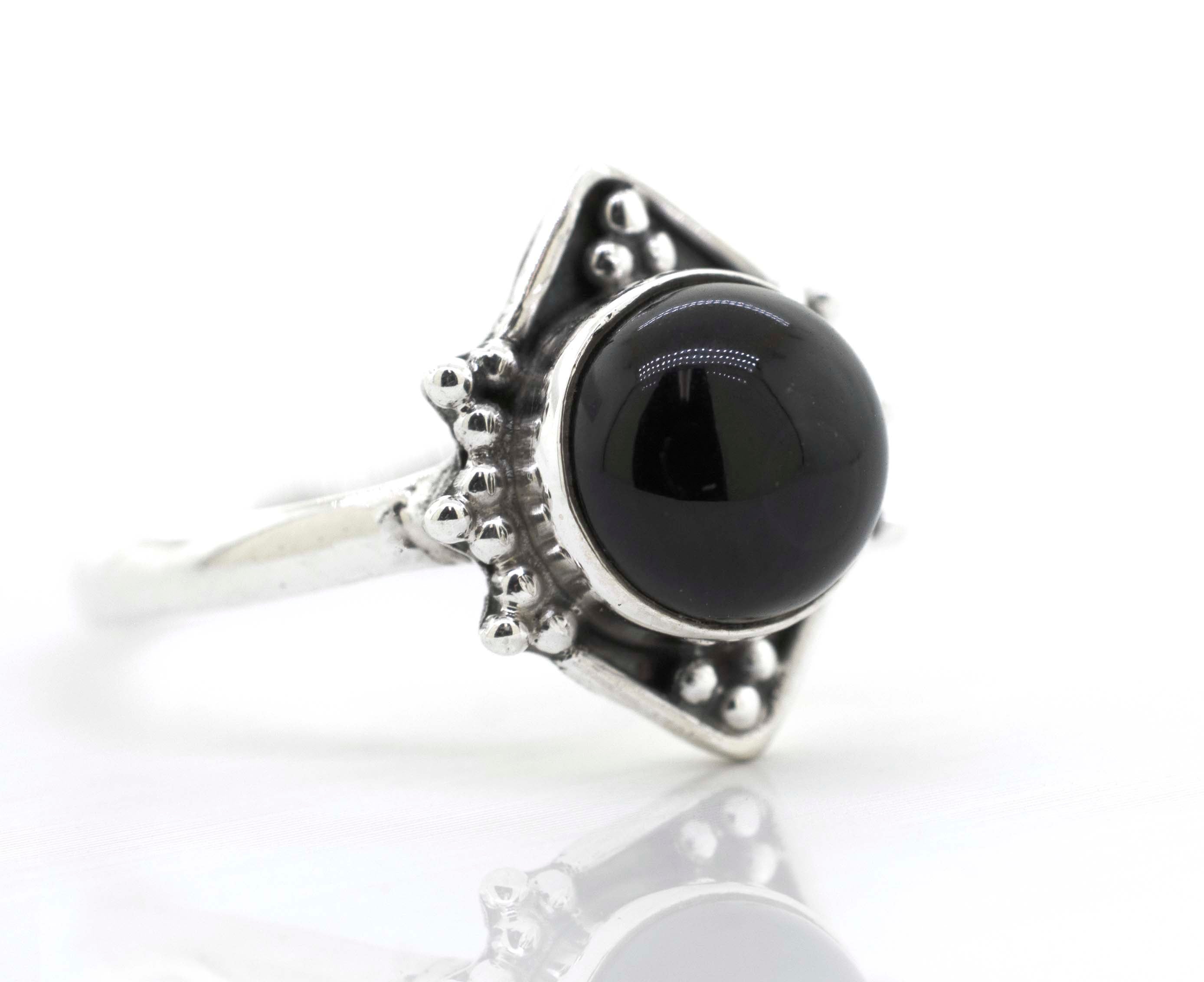 A Super Silver round gemstone ring with an oxidized diamond shape pattern, featuring a black onyx gemstone, on a white surface.