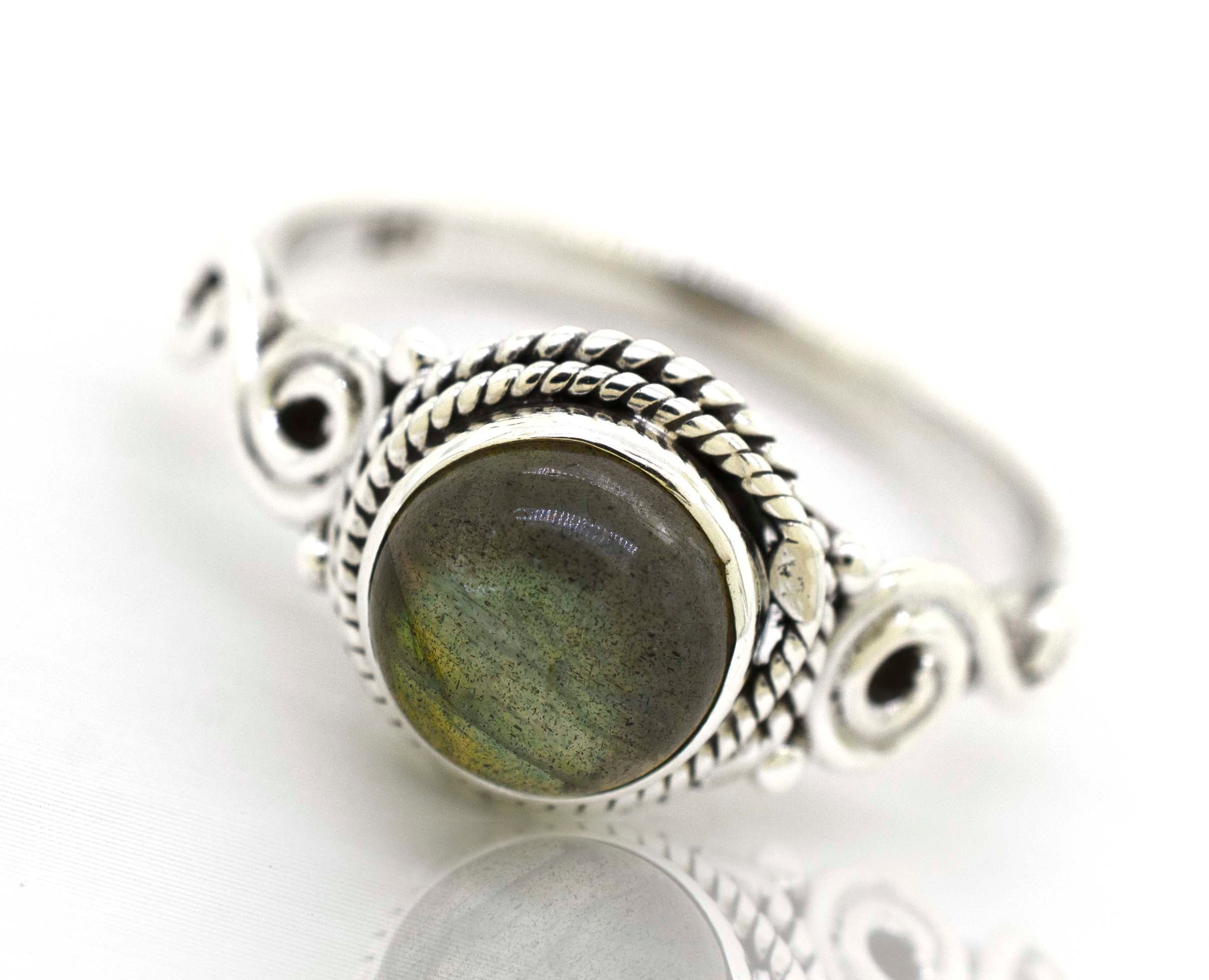 This stunning Super Silver Labradorite ring captures a bohemian vibe with its mesmerizing Gemstone Circle Ring With Rope Border And Swirl Design. Made with .925 sterling silver, this circle ring is an exquisite piece of jewelry.