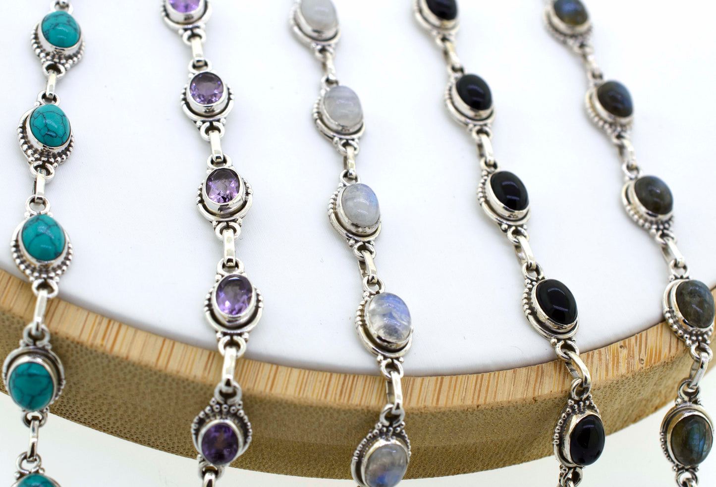 A chic display of Super Silver's Oval Gemstone Bracelets With Half Ball Border on a bohemian wooden stand.