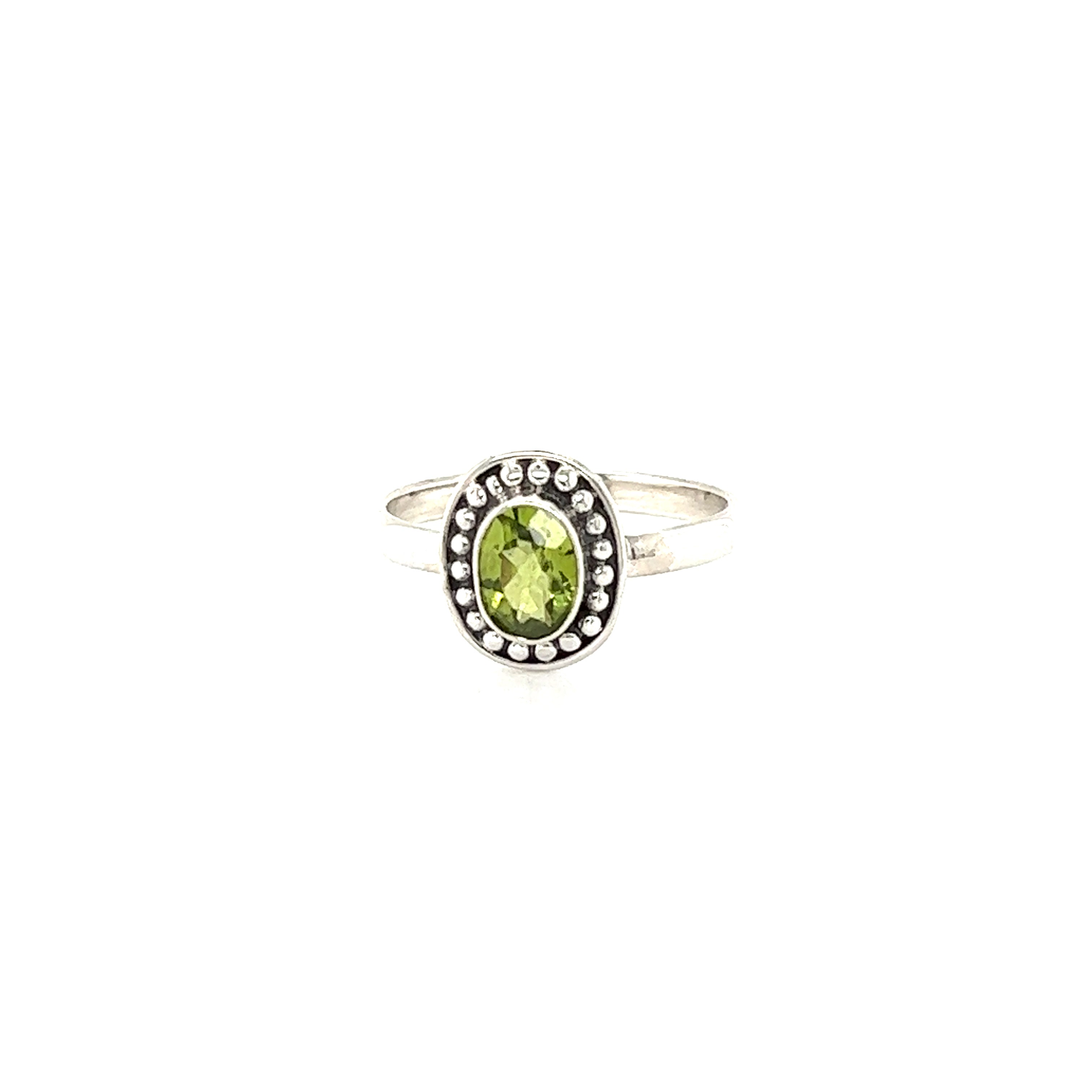 A oval gemstone ring with ball disk border with diamond accents.