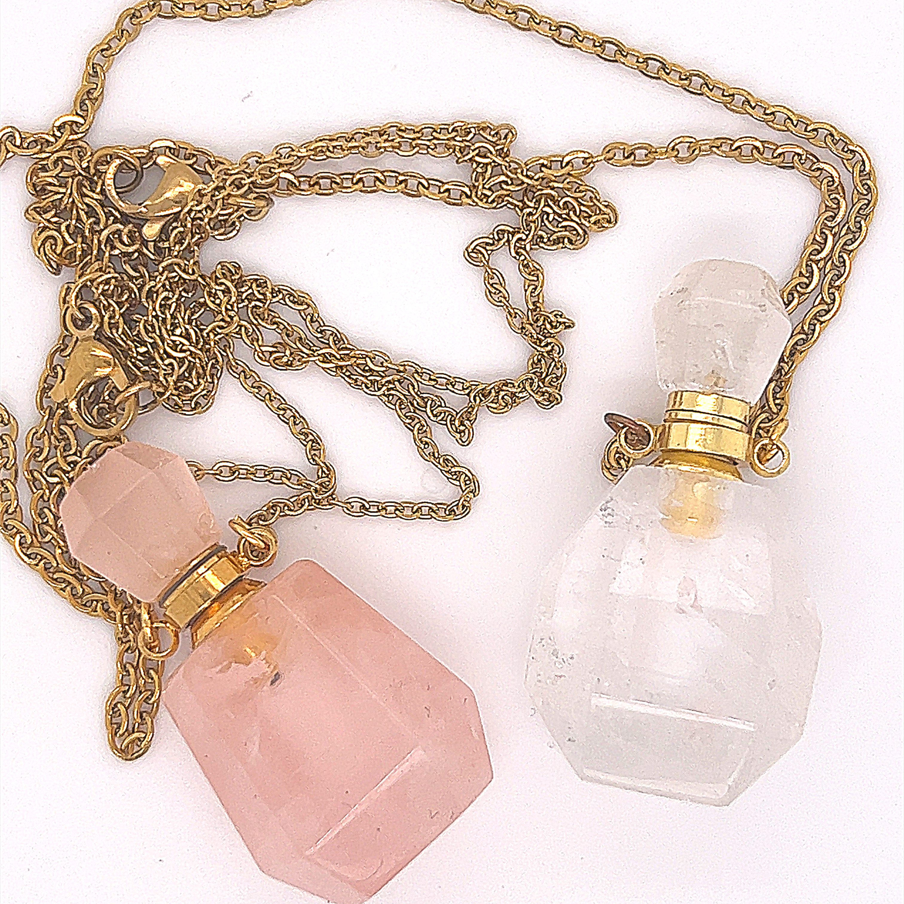 Two Crystal Perfume Vial Necklaces on gold chains—one with a pink vial, one clear—are displayed on a white background, each resembling an elegant rose quartz pendant.