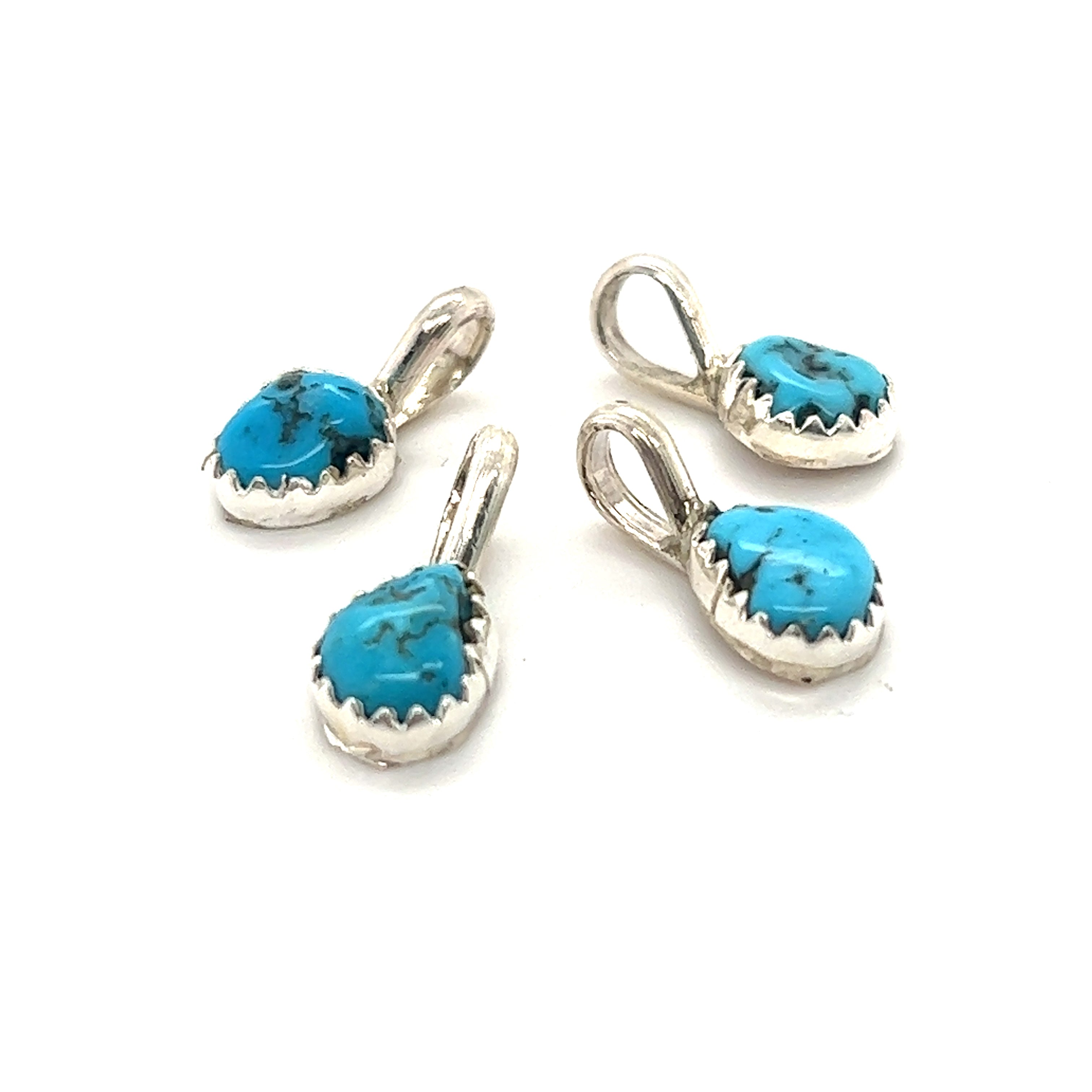 Four Teeny Tiny Native American Turquoise Nugget Pendants in a Super Silver claw tooth frame on a white background.