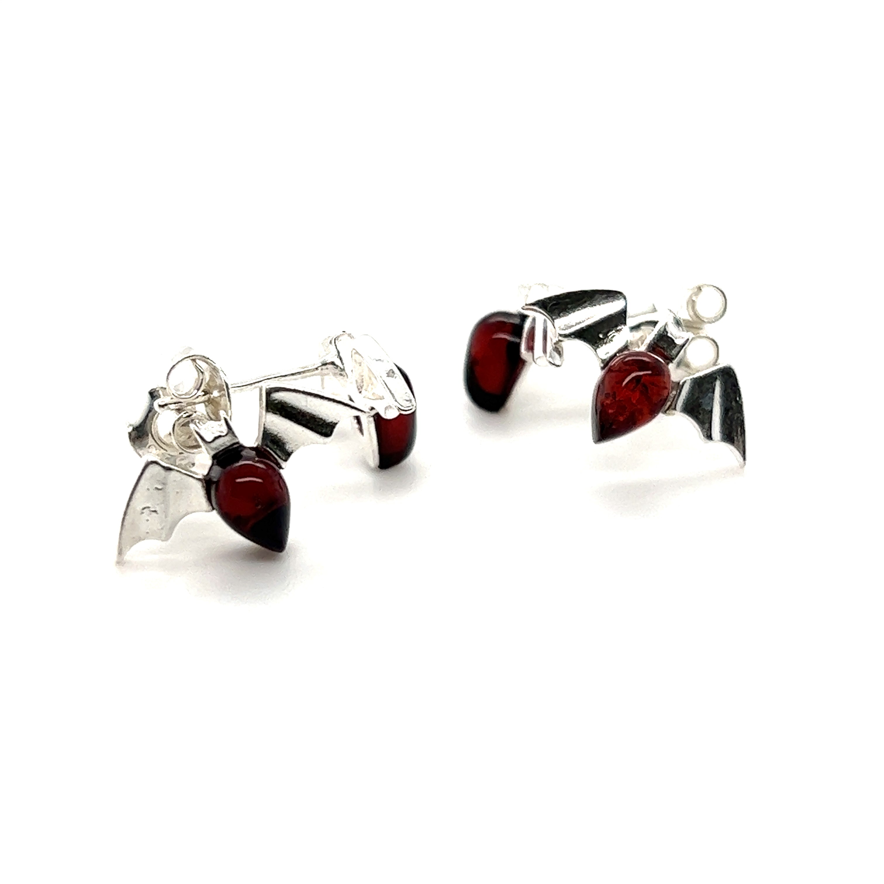 A pair of Enchanting Baltic Amber Bat Stud Earrings by Super Silver with cherry-colored glass.
