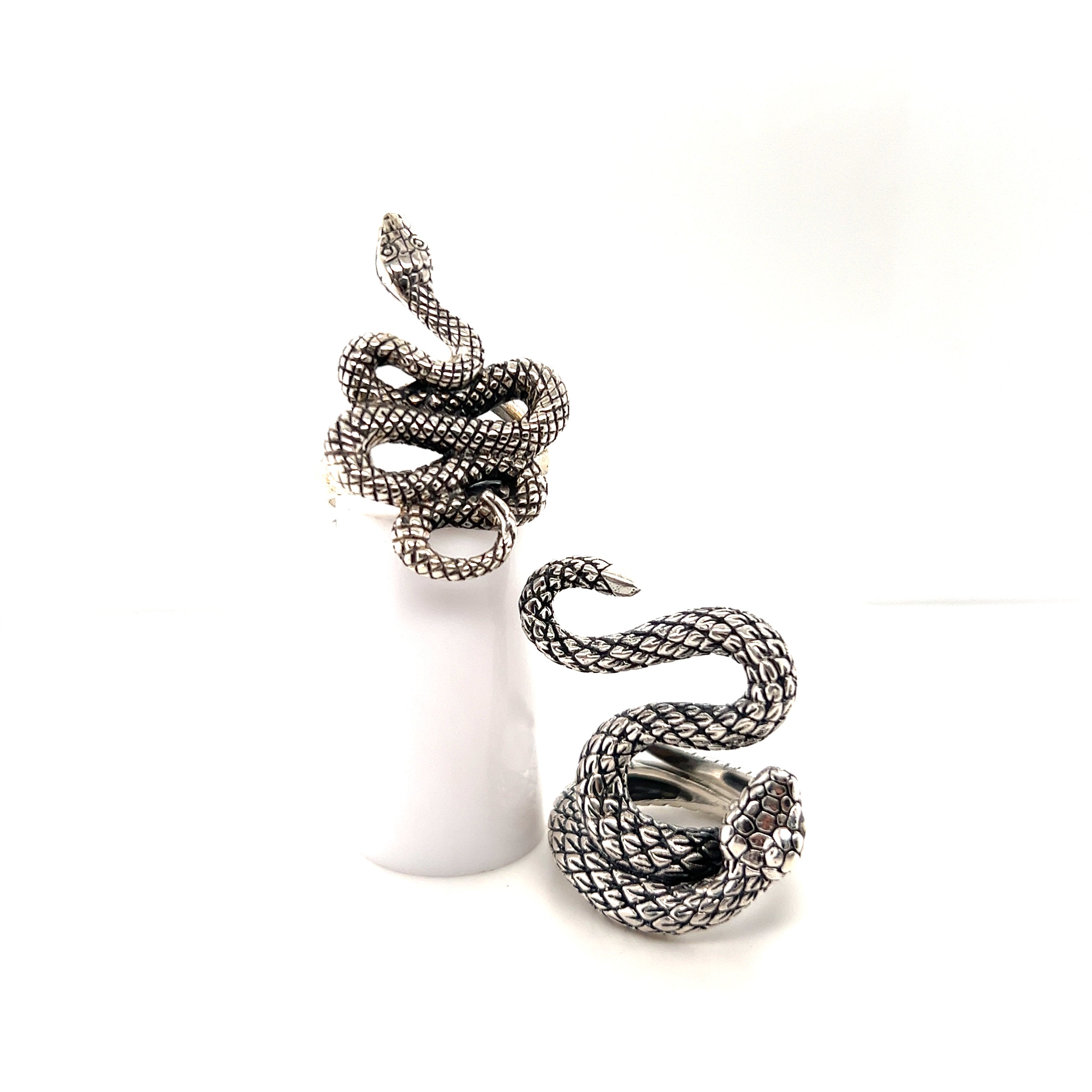 An adjustable pair of Bold Designer Snake Rings on a white table.