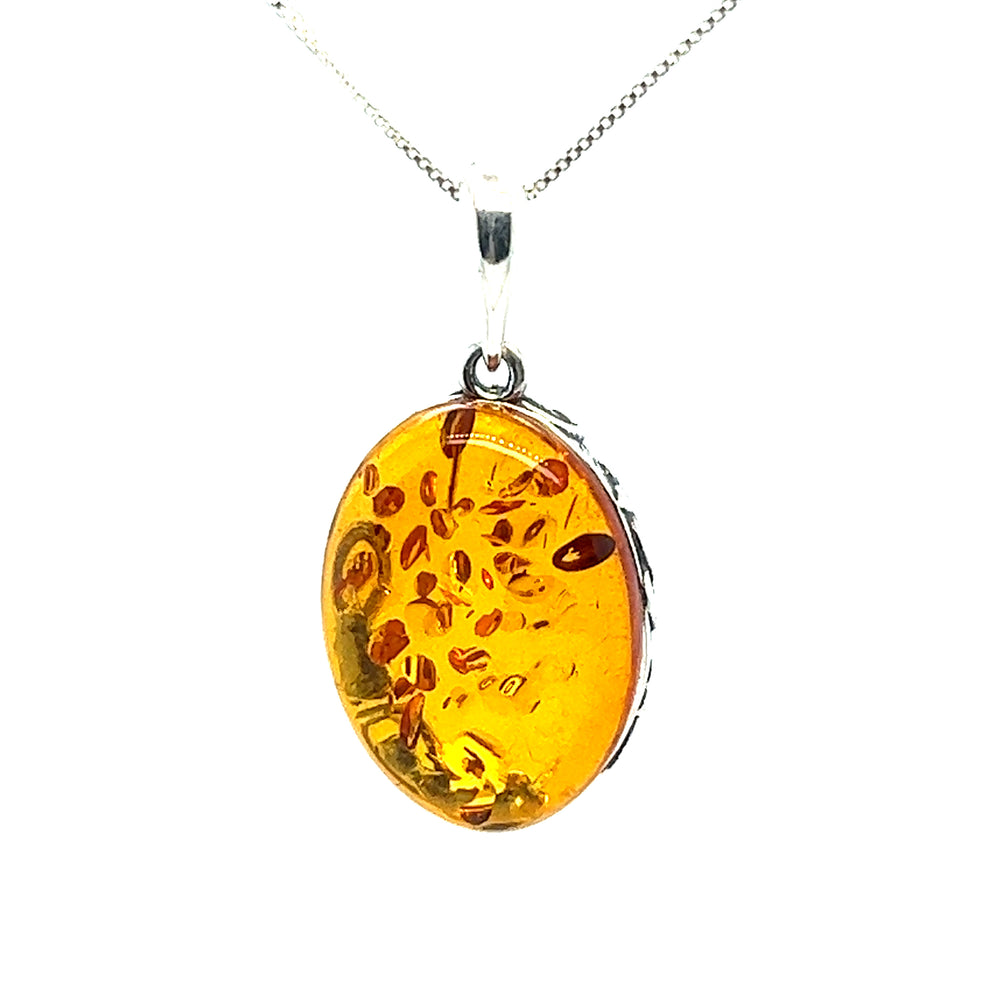 A vintage-styled Cognac Amber Oval Pendant with Floral Border featuring a yellow amber glass on a Super Silver chain.