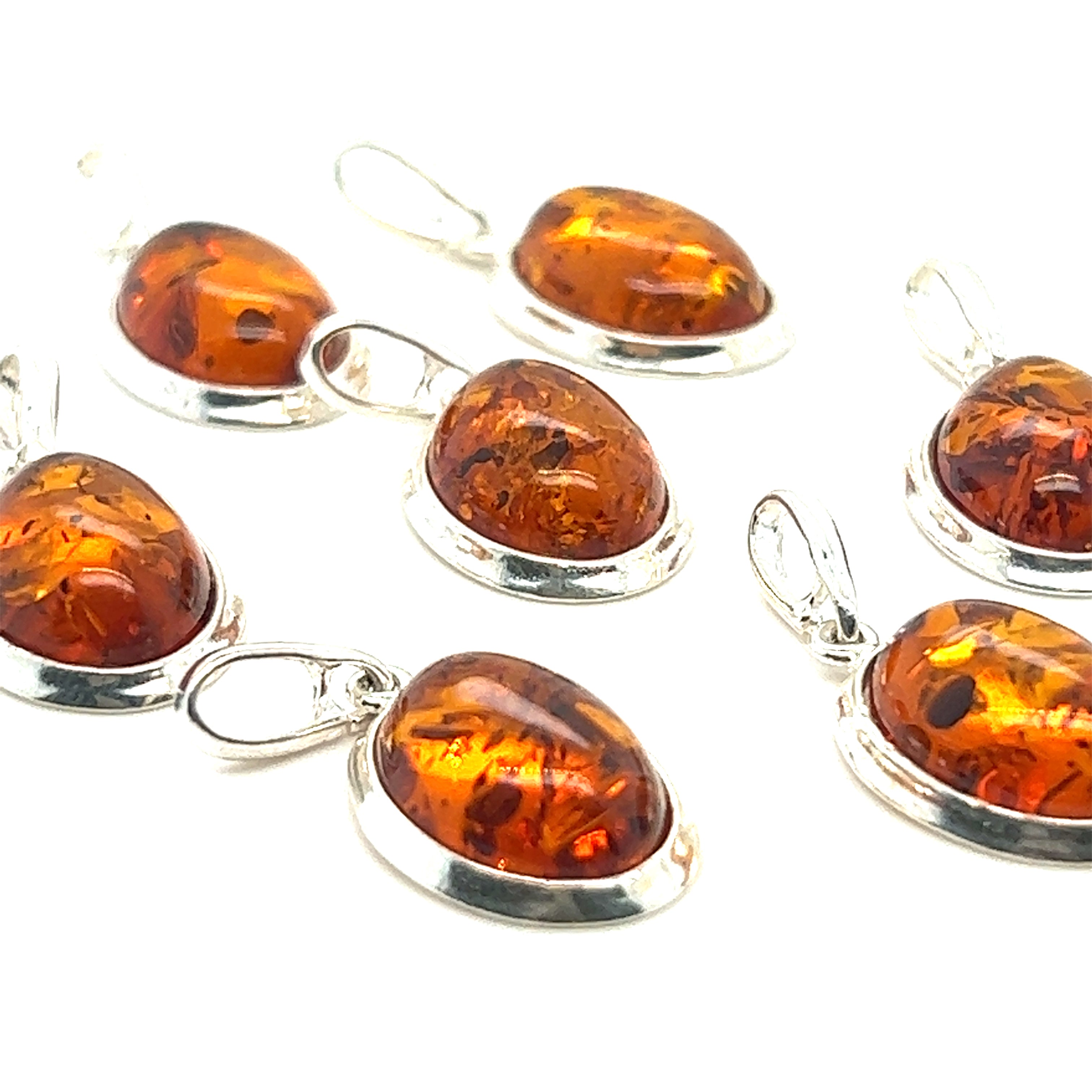 A collection of Simple Framed Oval Amber Pendants featuring Super Silver sterling silver bezels, showcased on a crisp white background.