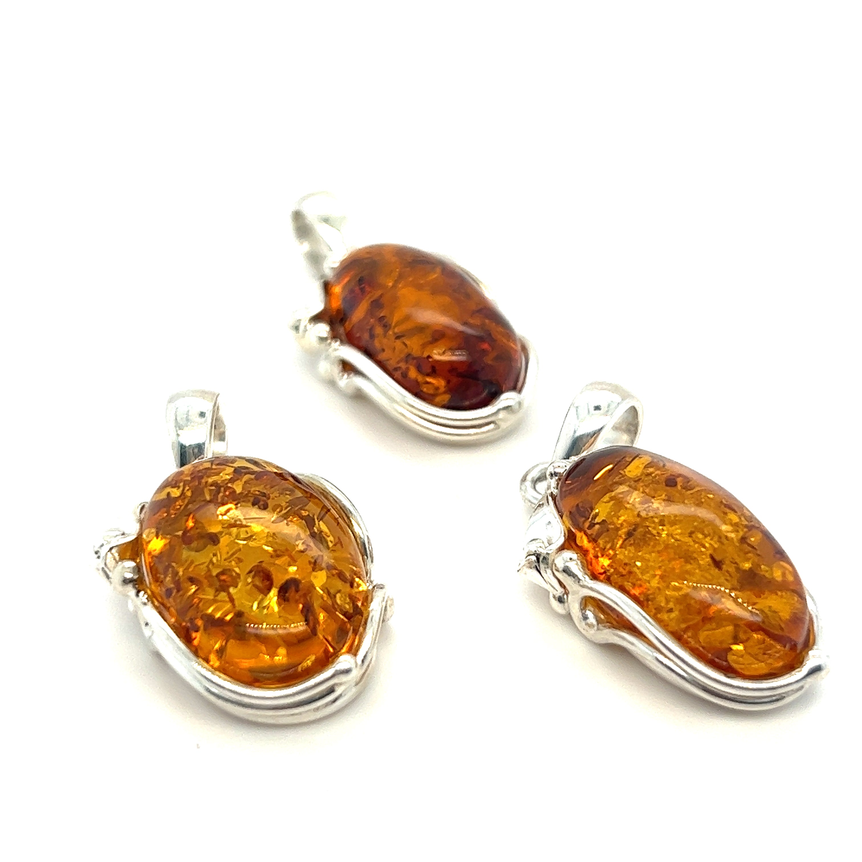 Three stunning Amber Oval Pendants with silver vines on a white background from Super Silver.