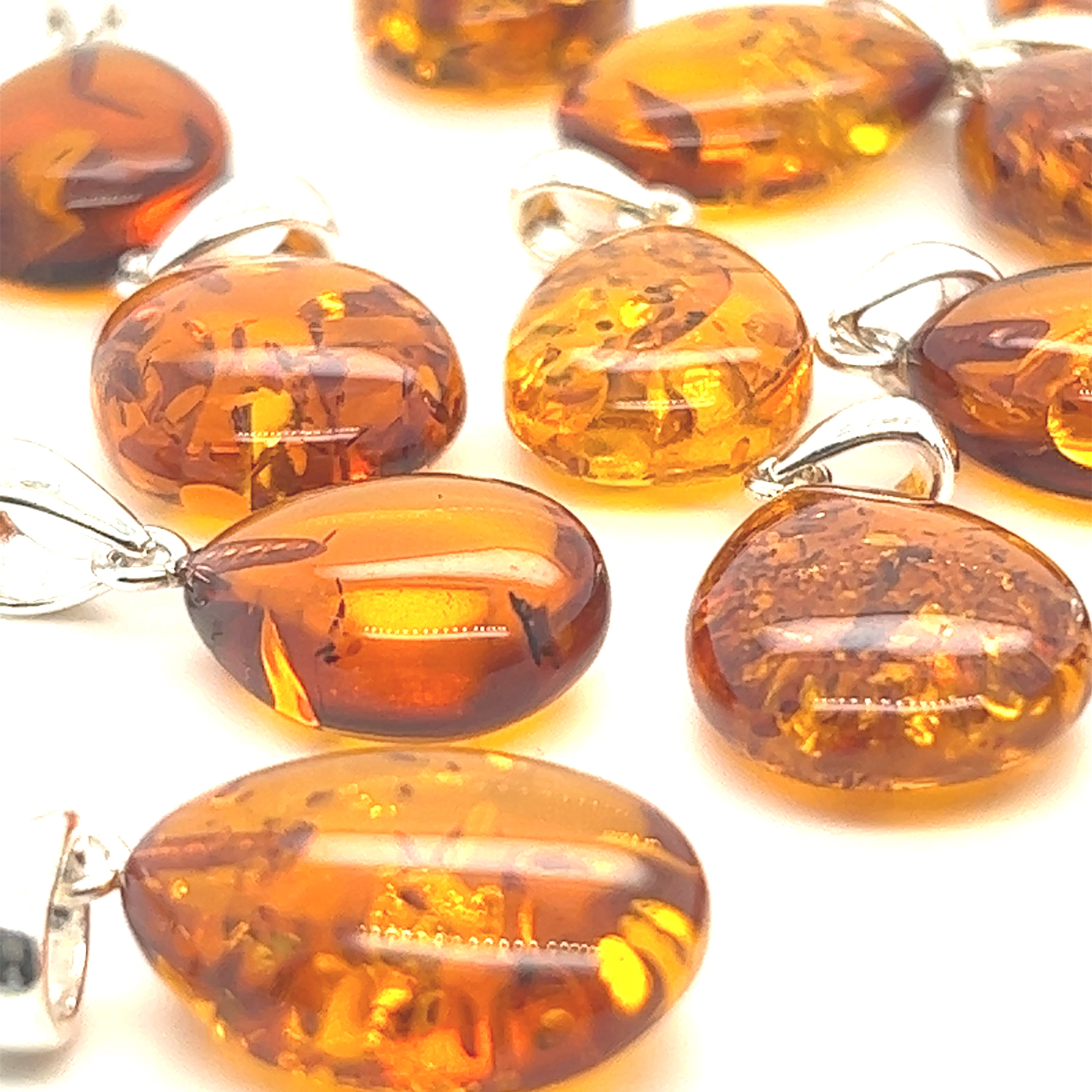 A collection of Super Silver Teardrop Amber Pendants exuding healing energy, beautifully displayed on a pristine white surface.