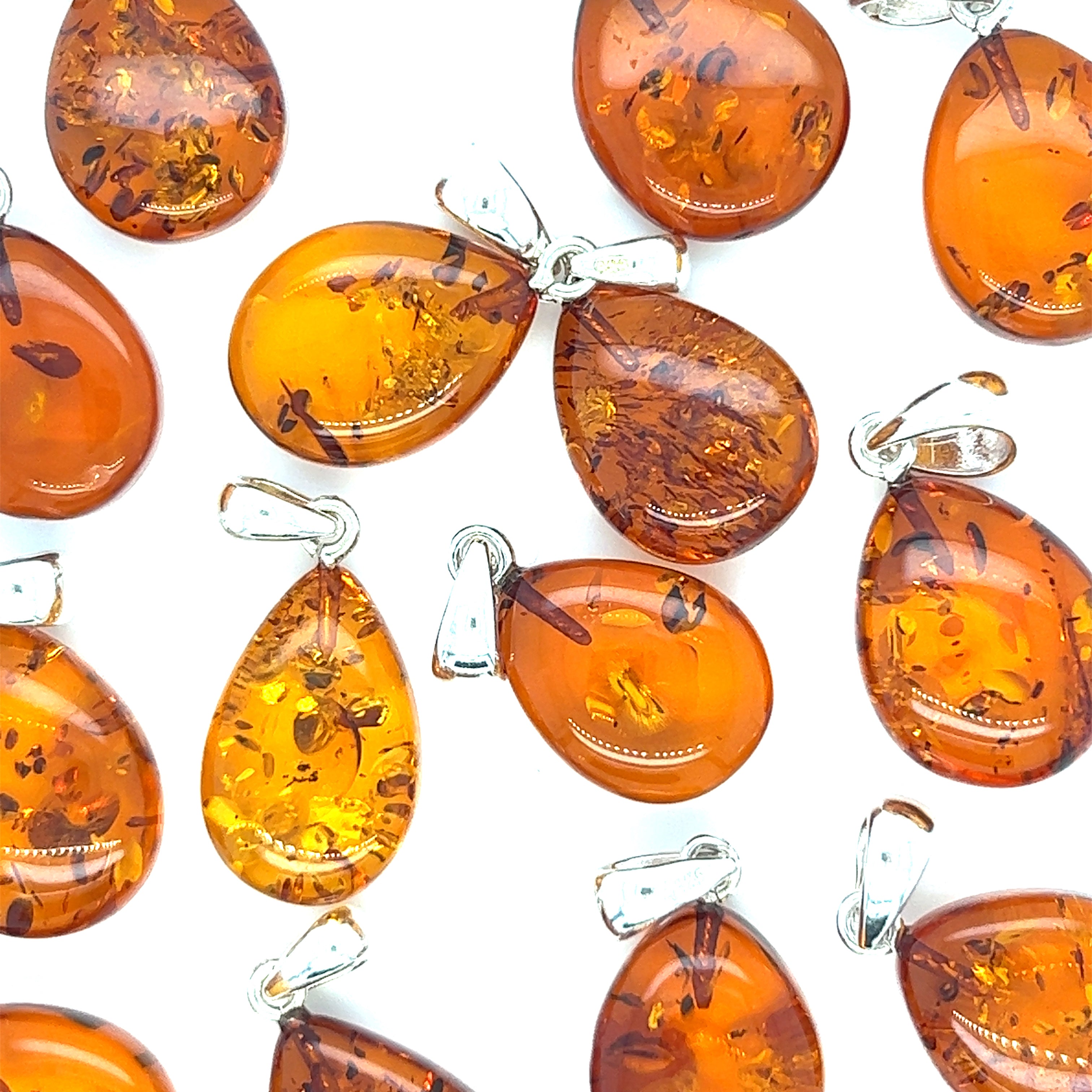 A collection of Teardrop Amber Pendants by Super Silver, radiating healing energy, showcased on a serene white background.