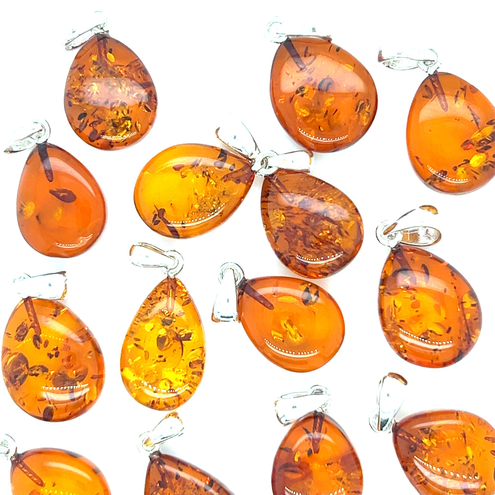 
                  
                    A group of Super Silver Teardrop Amber Pendants on a white background.
                  
                